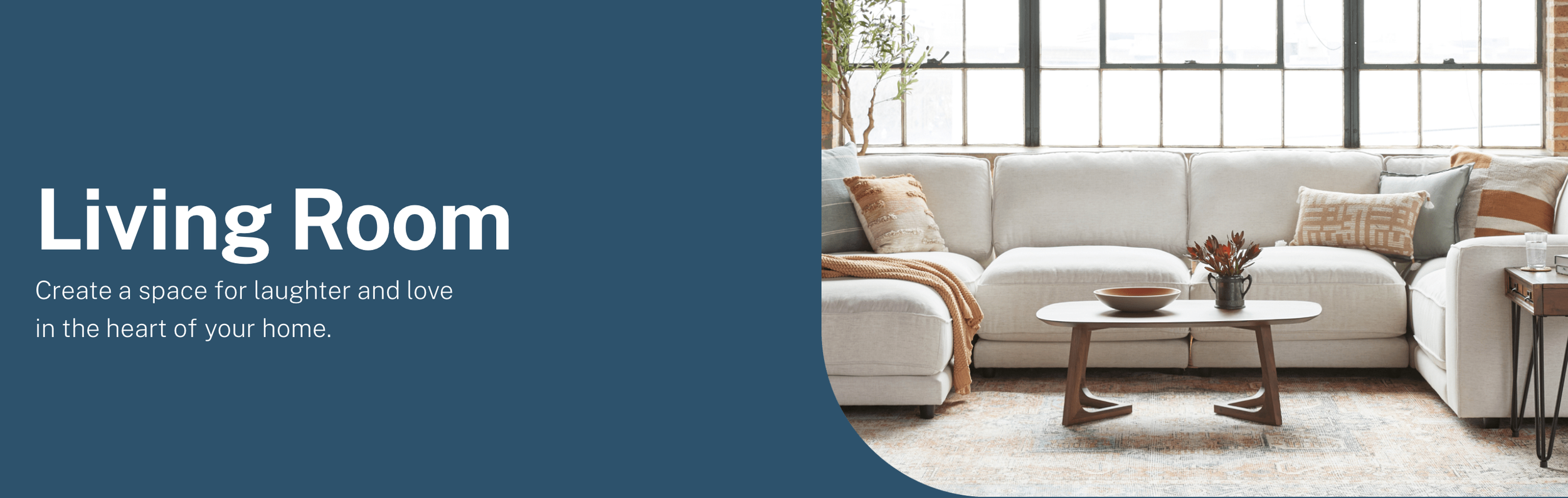 Living room with large window, white sectional sofa, decorative pillows, wooden coffee table, and potted plant.