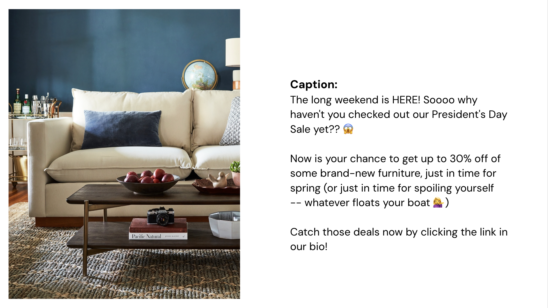 Living room with a beige sofa, dark blue wall, coffee table with a bowl of apples, books, and decorative items, and a bar cart with bottles in the background.