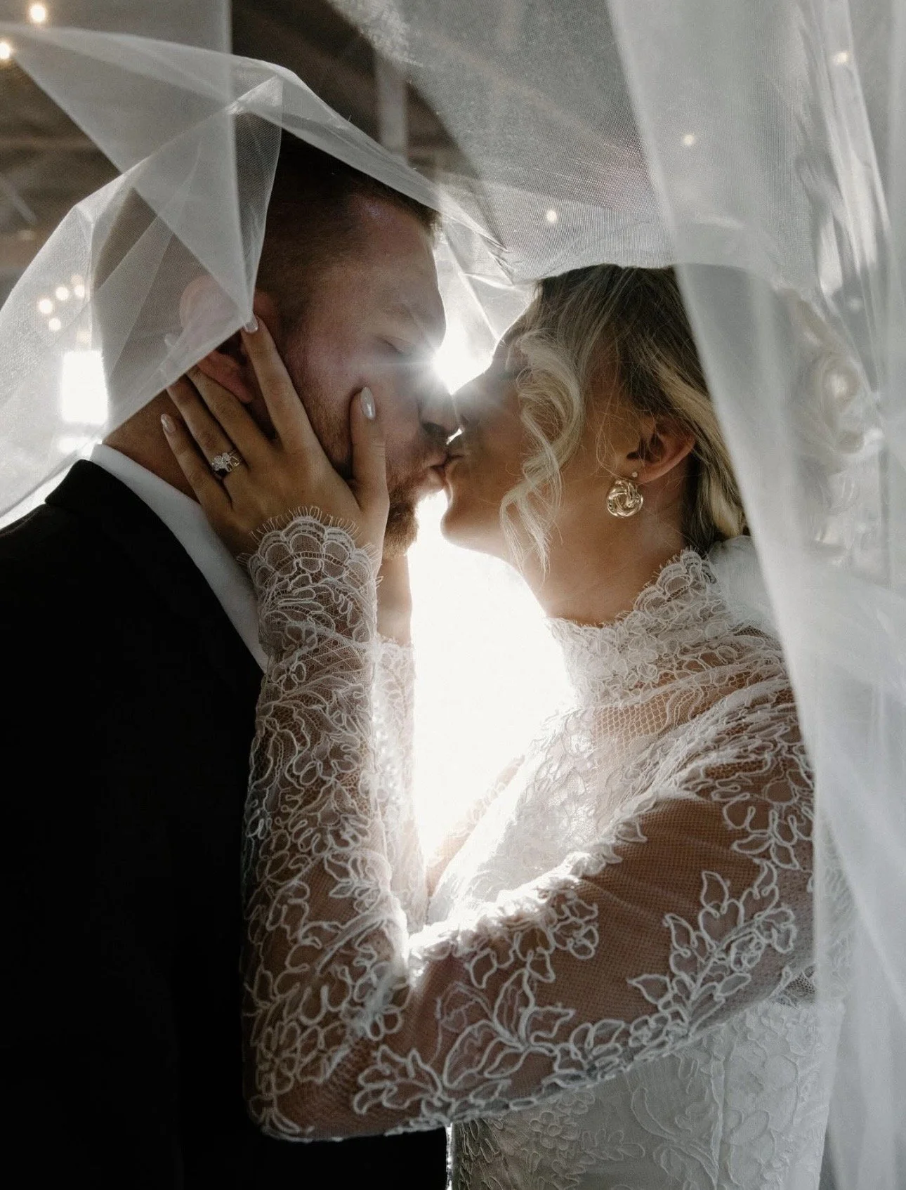 Delaney and her husband kissing under her wedding veil.