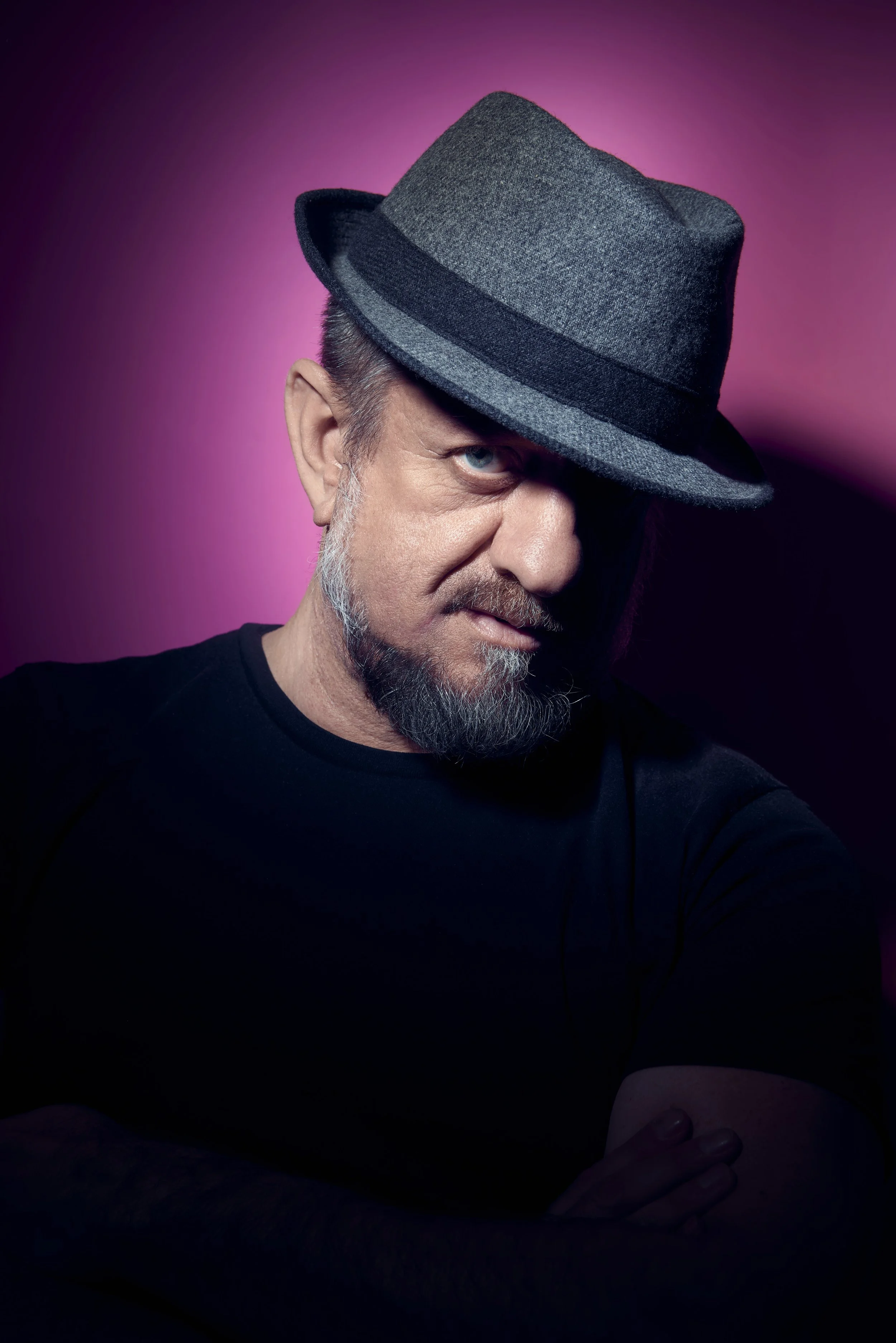 Ritratto di un uomo con cappello grigio e camicia nera, sfondo rosa