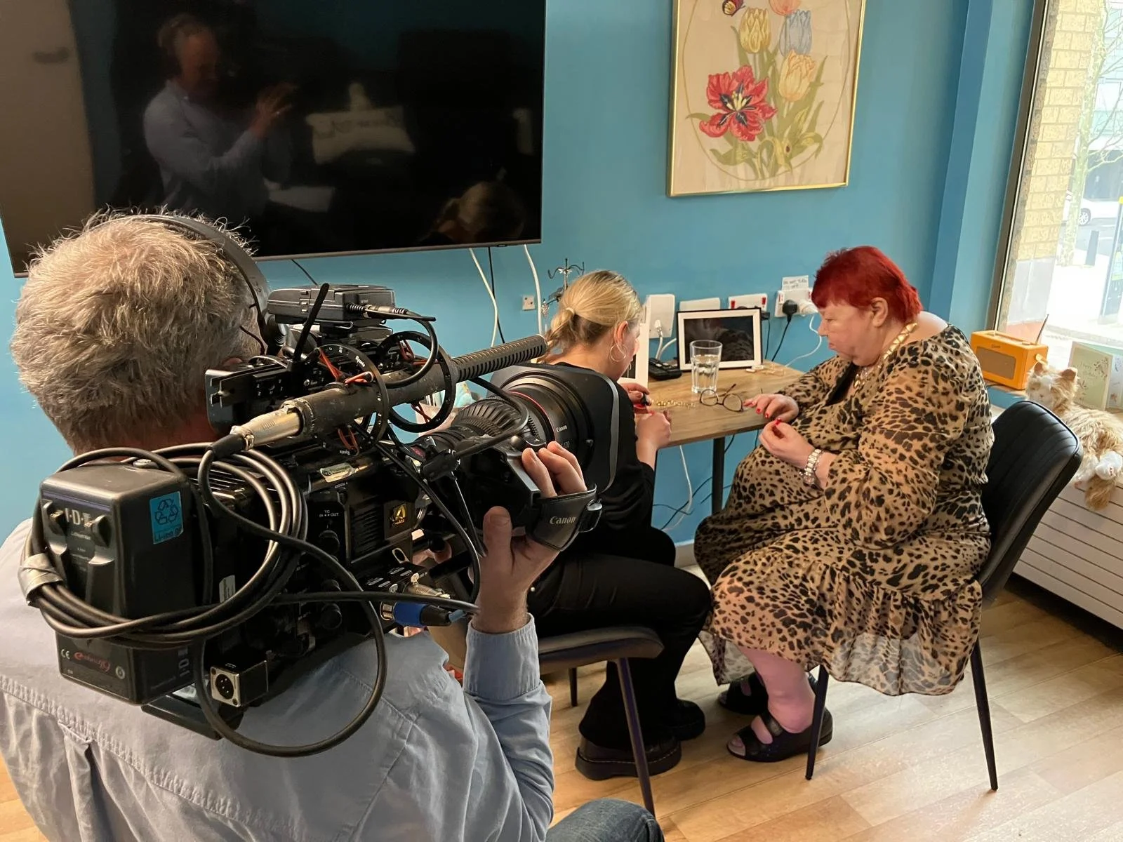 A woman has her nails done by a carer as she is filmed for a Legacy Film she commissioned to celebrate her life and achievements.  She is happy, engaged and enjoying the process