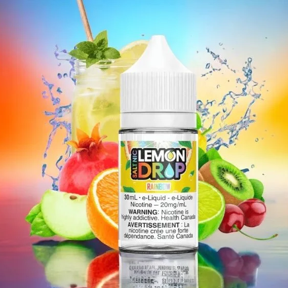 A bottle of Nic Salt Lemon Drop vape juice with lemon, pomegranate, orange, kiwi, and cherries surrounding it, and a rainbow-colored background with splashes of water.