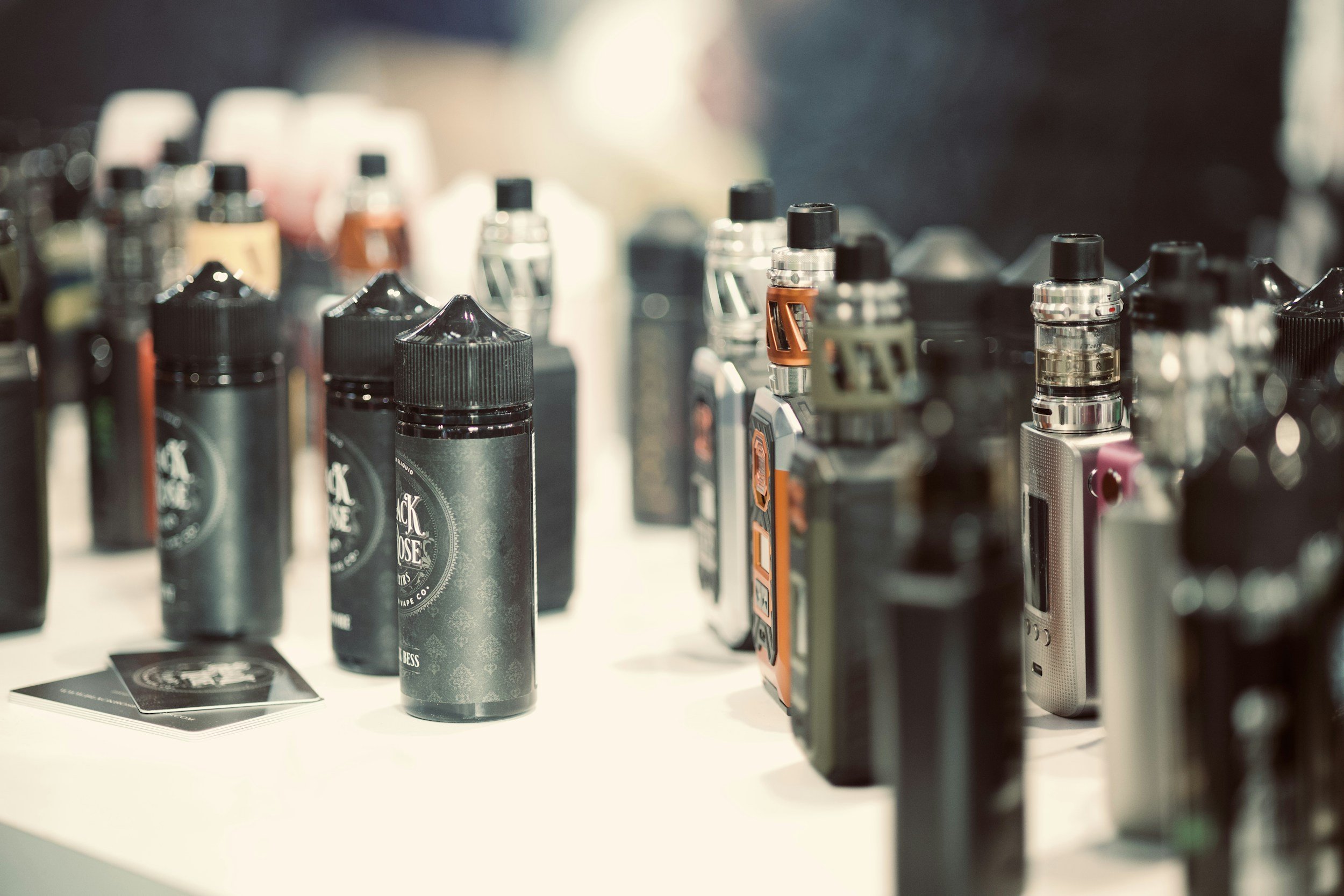 Various bottles of e-liquid for vaping displayed on a table.