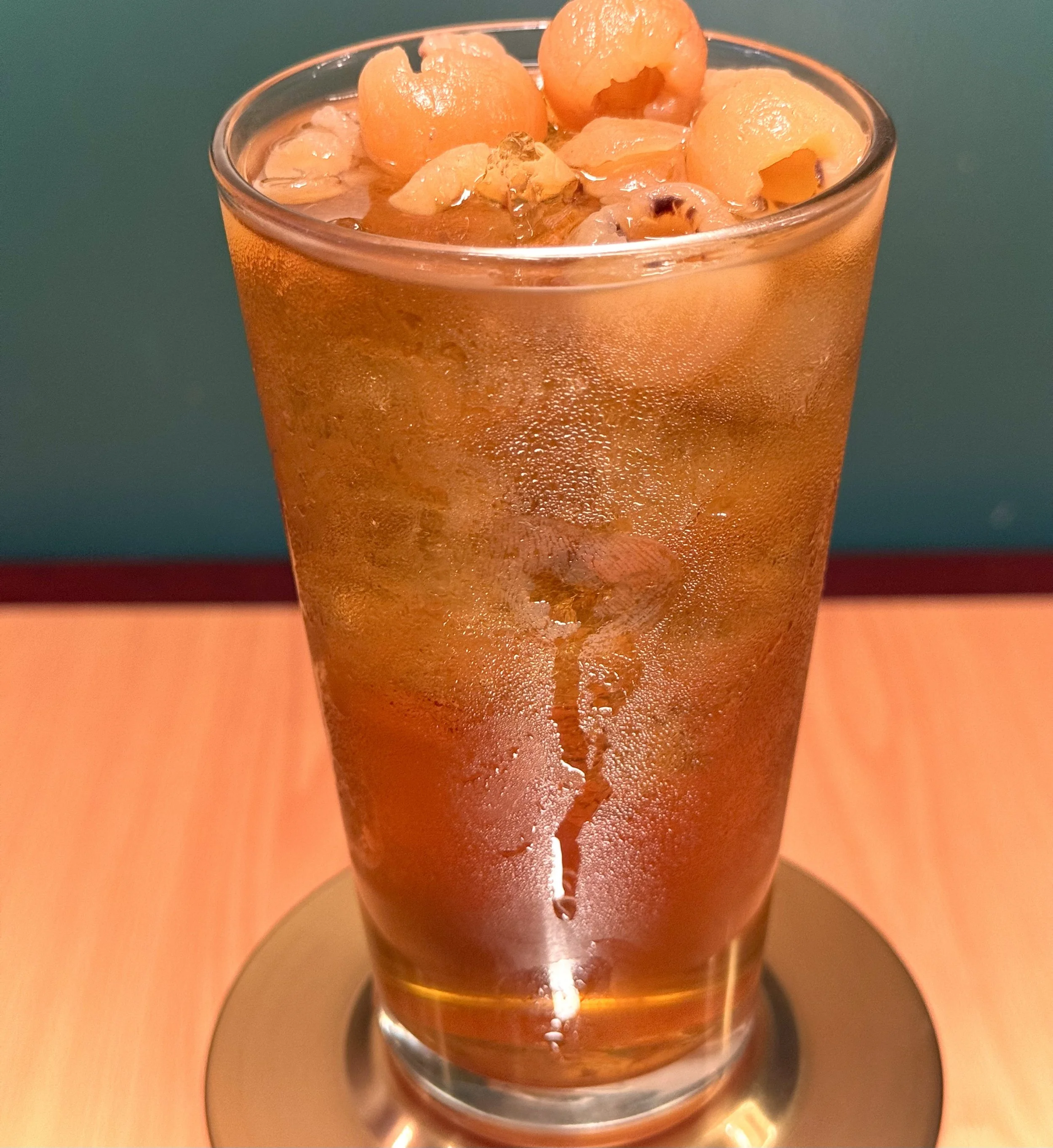 A tall glass of iced tea with ice cubes and peach slices