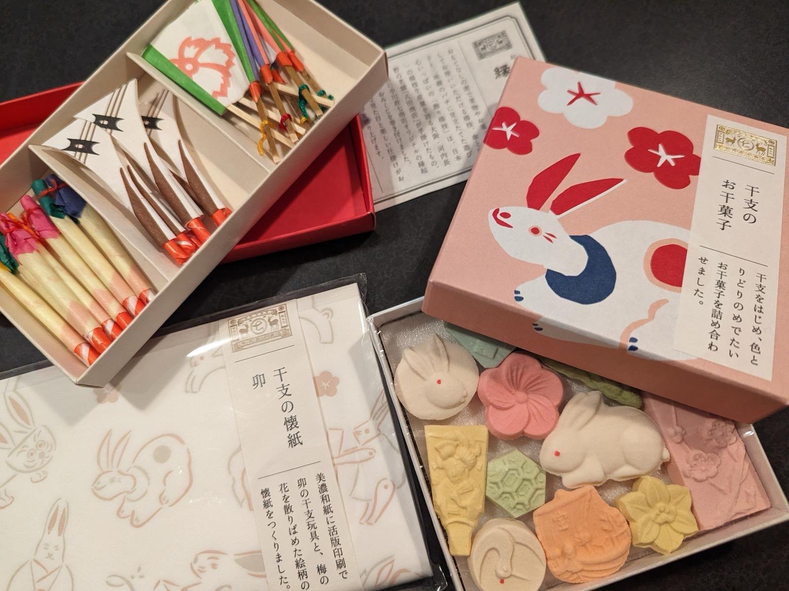 Various traditional Japanese confectionery and decorative items, including animal-shaped sweets and colorful sticks, displayed in decorated boxes.