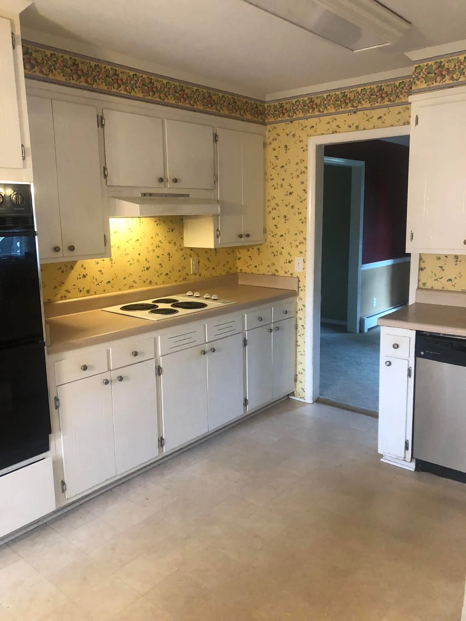 before kitchen range, outdated wallpaper and impractical lighting and storage