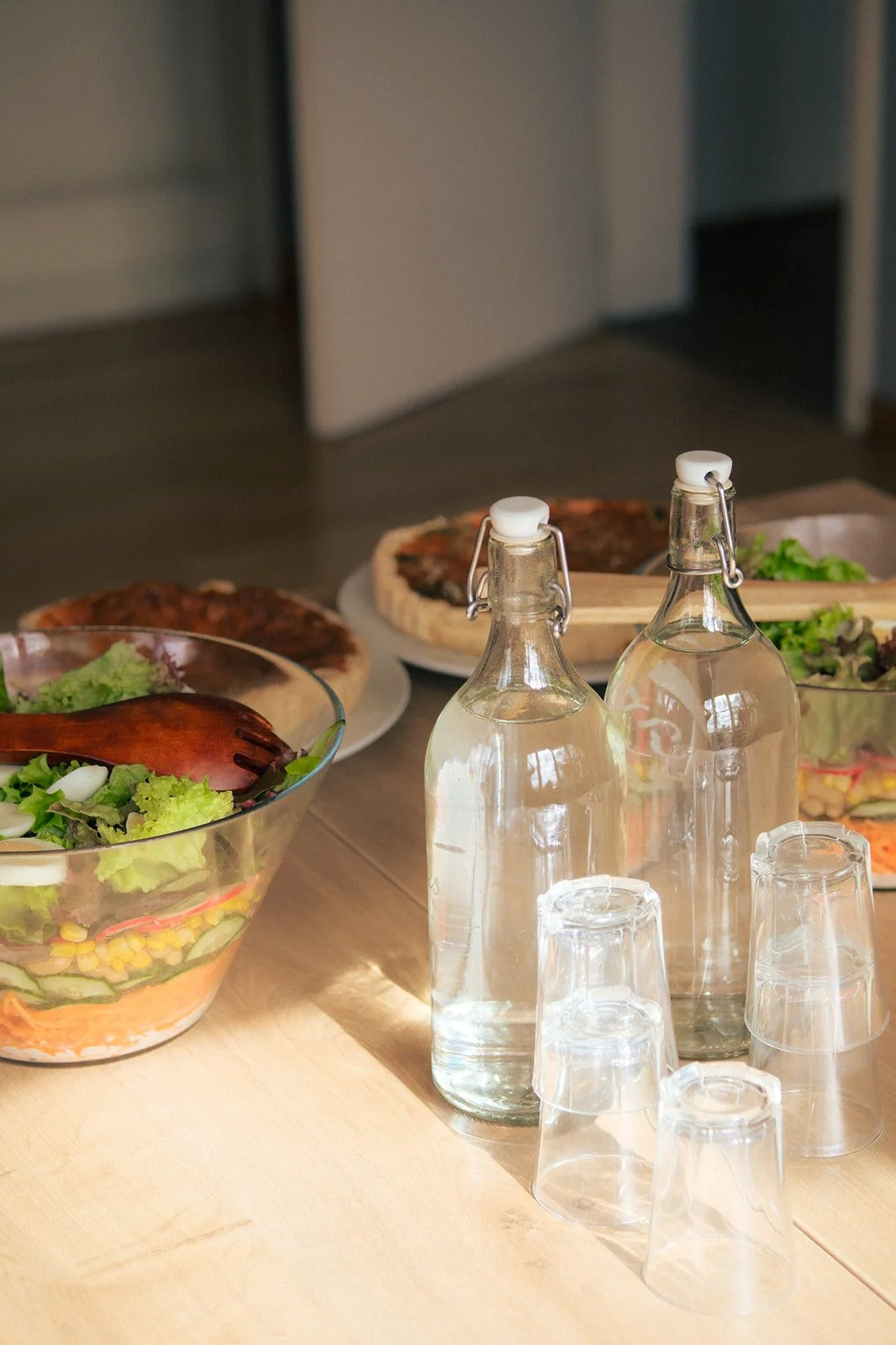 Exemple de lunch: buffet avec salades, quiches, boissons en bouteilles en verre et assiettes de nourriture.