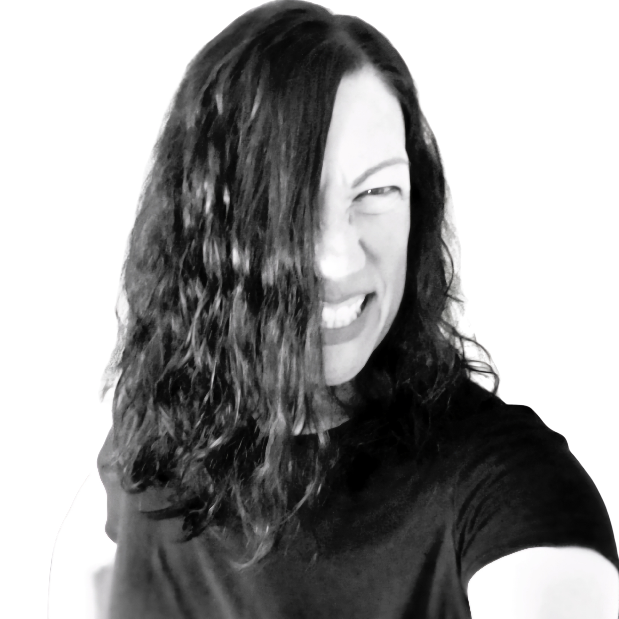 Close-up black and white portrait of a woman with long hair, smiling, with a white background.