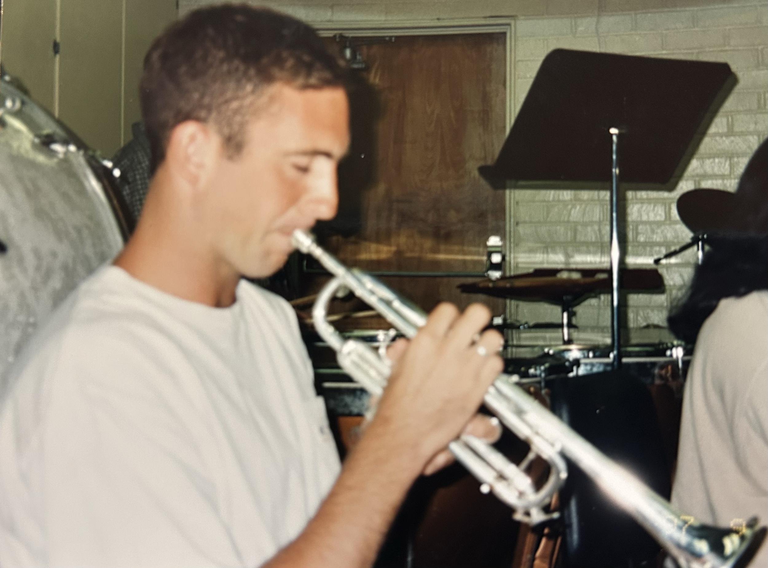 A man playing a silver flute in a music rehearsal or recording studio.