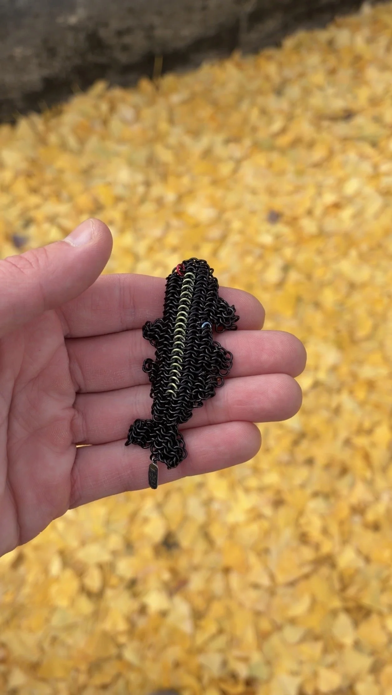 Side view of Ink Trout palm-scale trout sculpture — compact enameled copper and niobium contemporary art object by Emmit Flynn