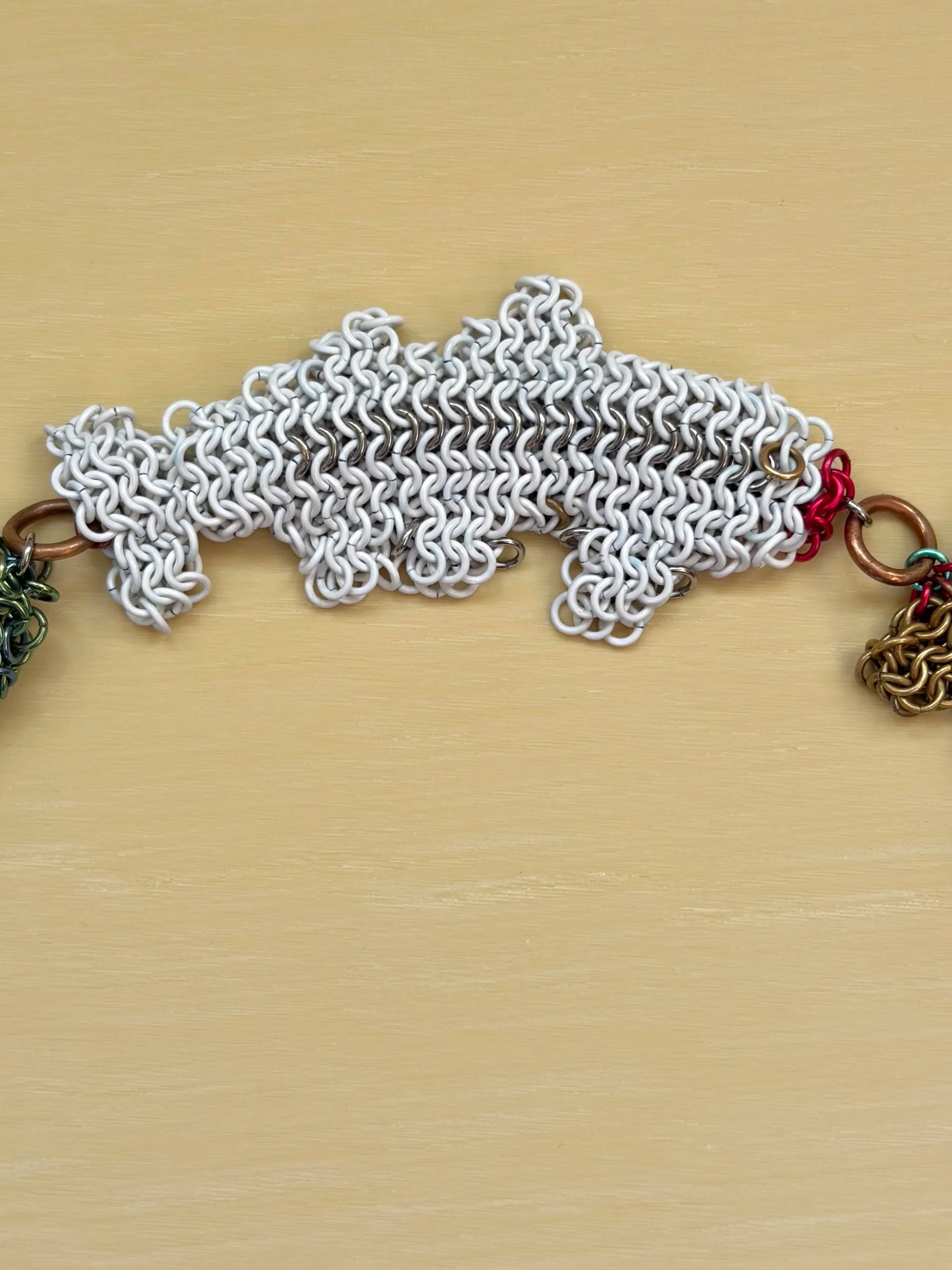 Dream Chain sculpture detail showing woven niobium trout amulets and orbital chain structure — contemporary art jewelry object by Emmit Flynn