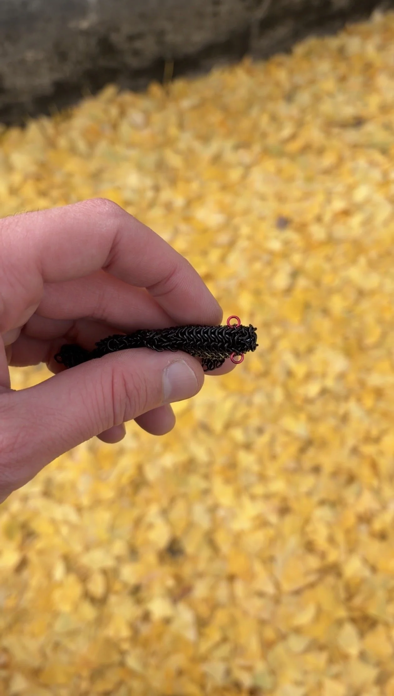Close-up detail of Ink Trout woven enameled copper chainmail sculpture with niobium centerline — tactile contemporary metal art