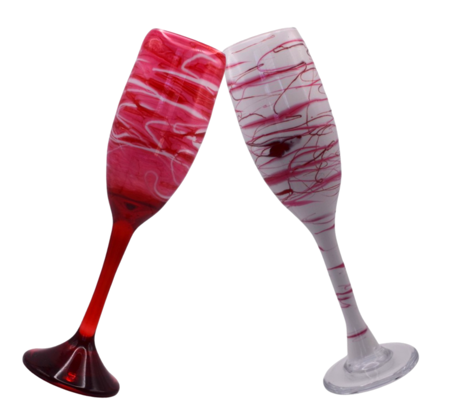 Two Hand spun custom champagne flutes, one with red and white swirls, and the other with pink and white swirls, clinking together.