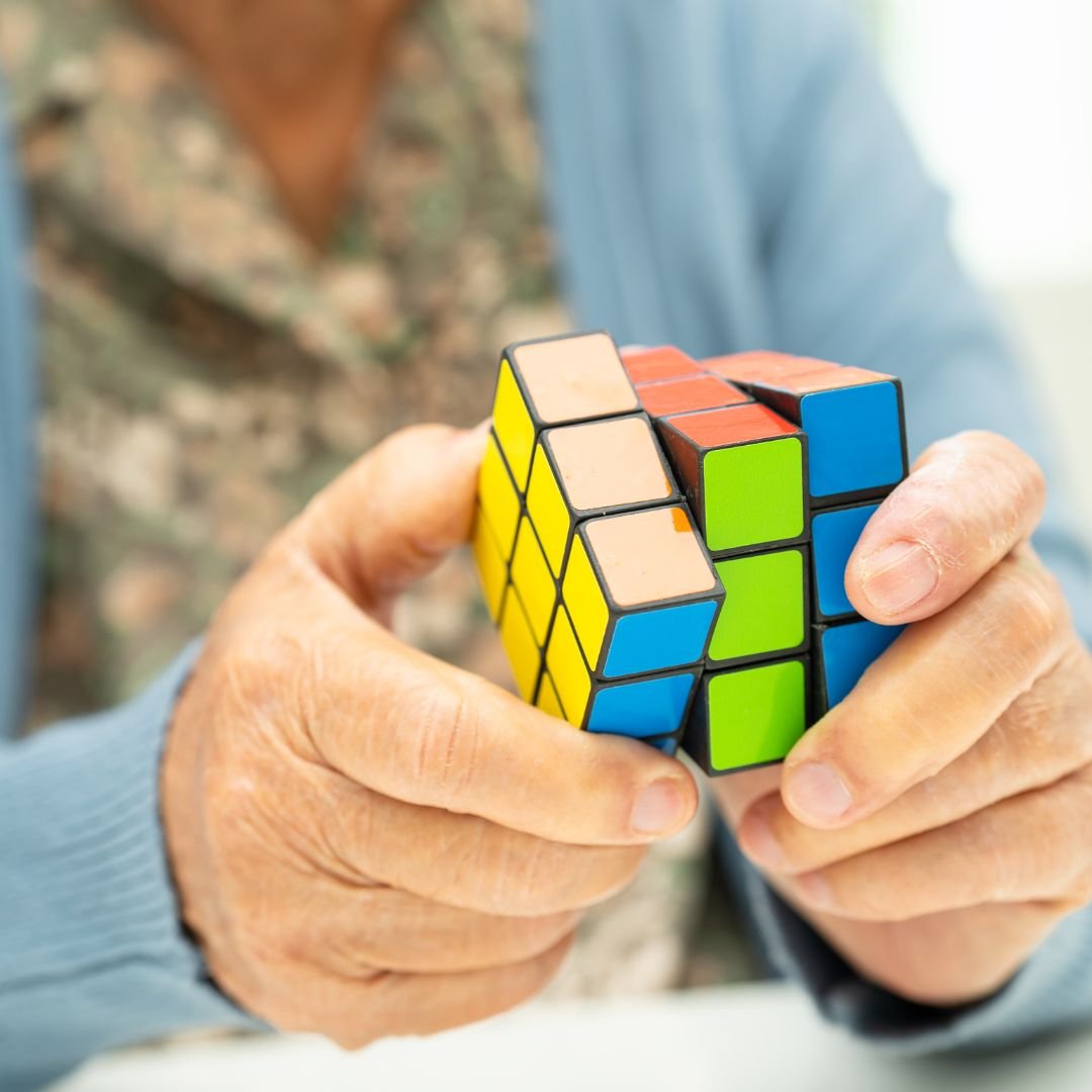 Mani anziane che manipolano un cubo di Rubik multicolore.