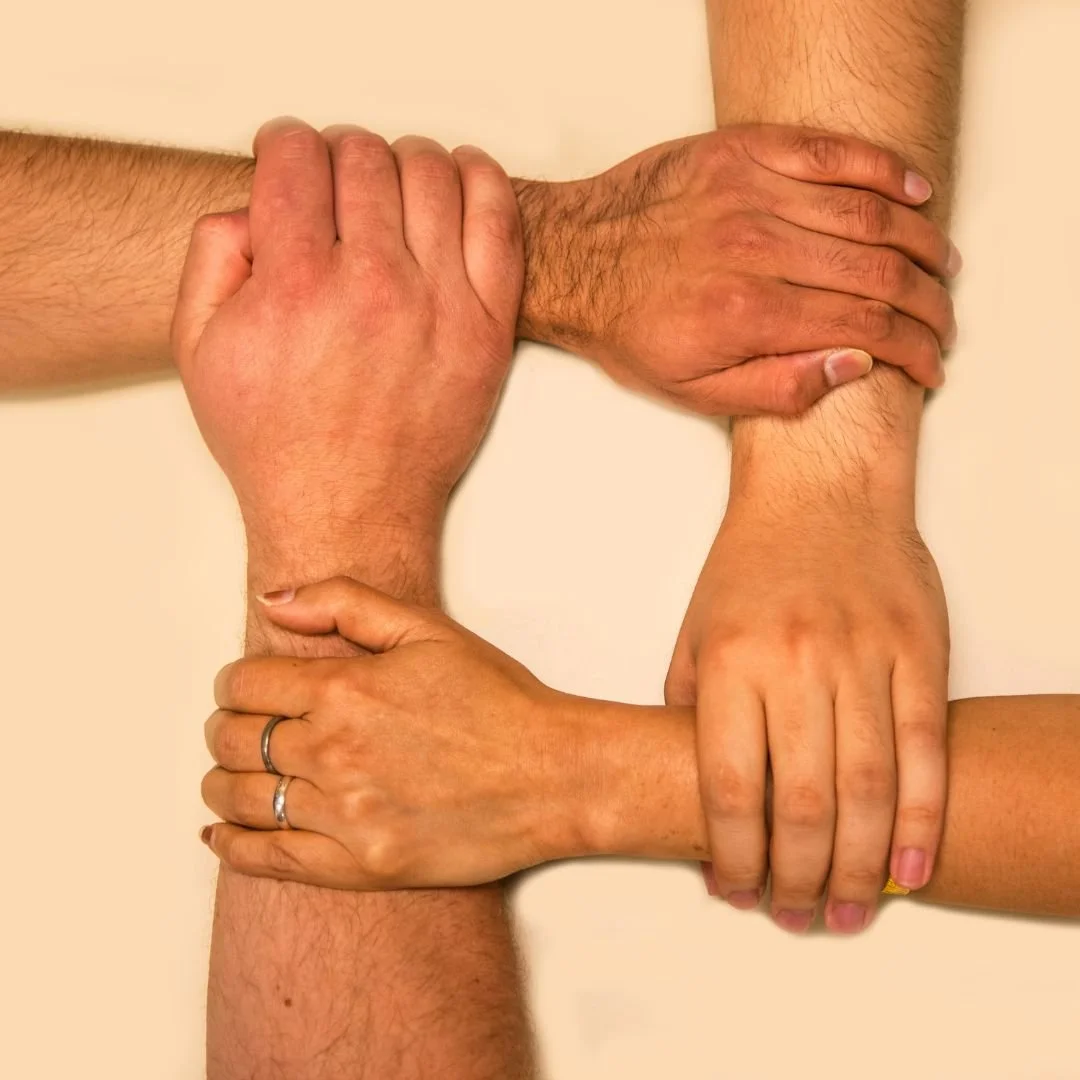 Quattro mani si uniscono formando un quadrato, ogni mano afferrando il polso dell'altra.