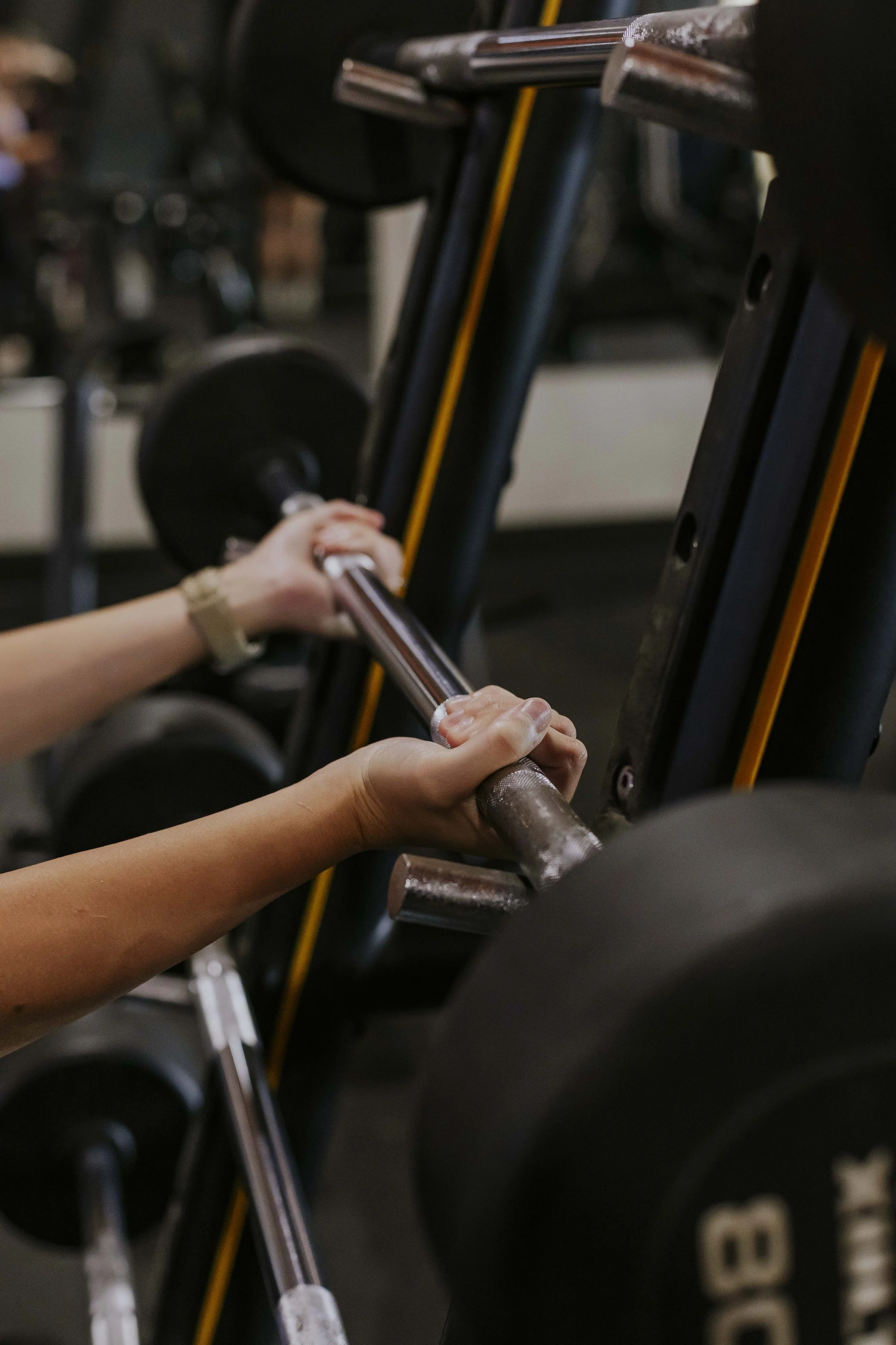 A person loading a barbell into a squat rack at the gym.