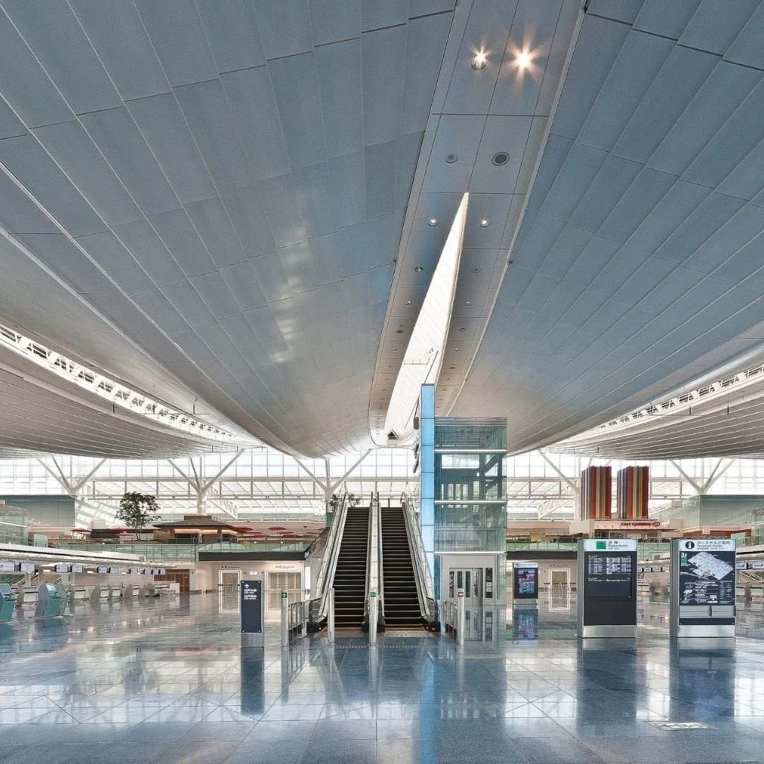 Empty modern airport terminal with escalators and digital information screens.