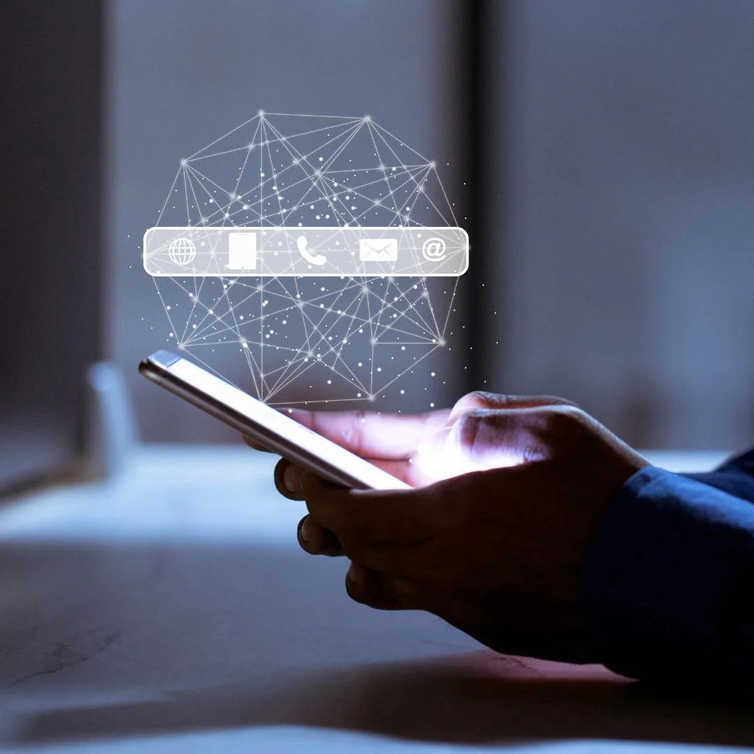Person holding a smartphone with holographic icons for web, phone, email, and at symbol