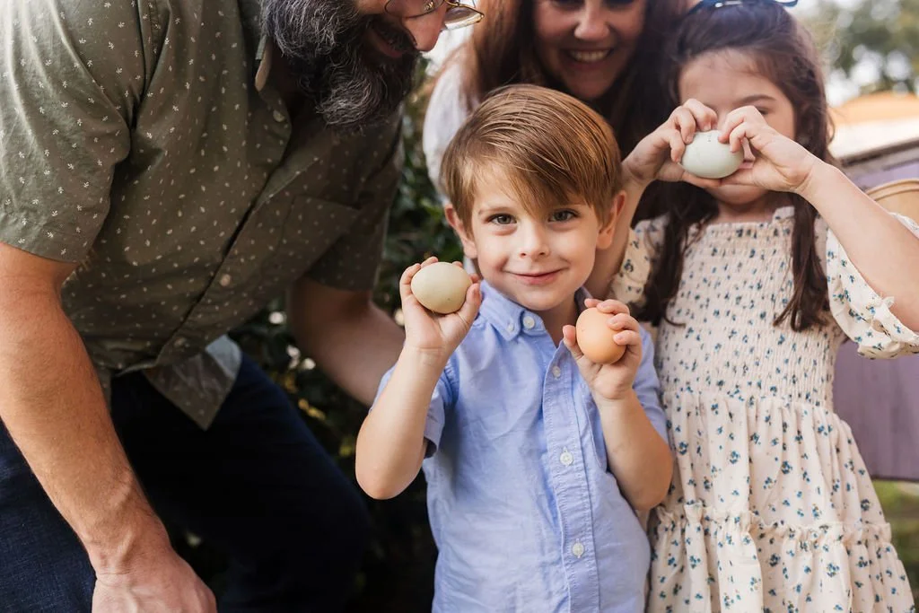 A family of four, including two children and two adults, holding eggs outdoors for an Easter celebration.
