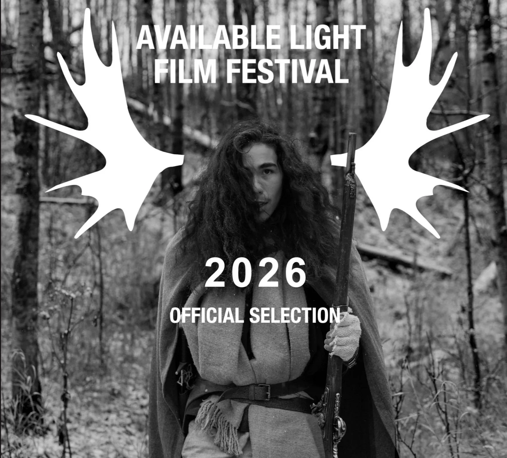 Scene from H&HA showing a black and white photo of a man with long curly hair holding a rifle in a forest, with text overlay advertising the 2026 Available Light Film Festival.