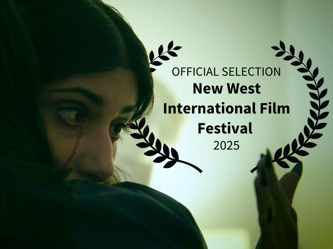 Scene from Immortal Embrace showing a young woman with dark hair and makeup, featuring a red streak on her face, looks over her mothers shoulder. Superimposed text indicates  official selection for the New West International Film Festival 2025.