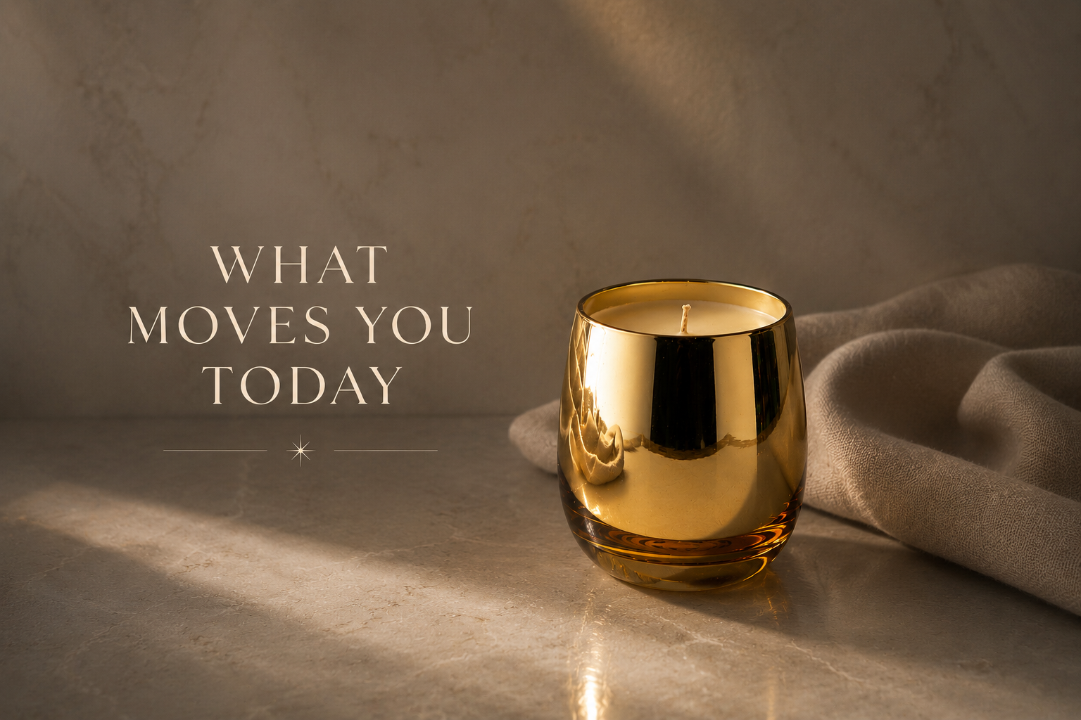 A lit candle in a reflective gold holder sitting on a textured surface with a soft fabric nearby, with the words 'What moves you today' written to the left.