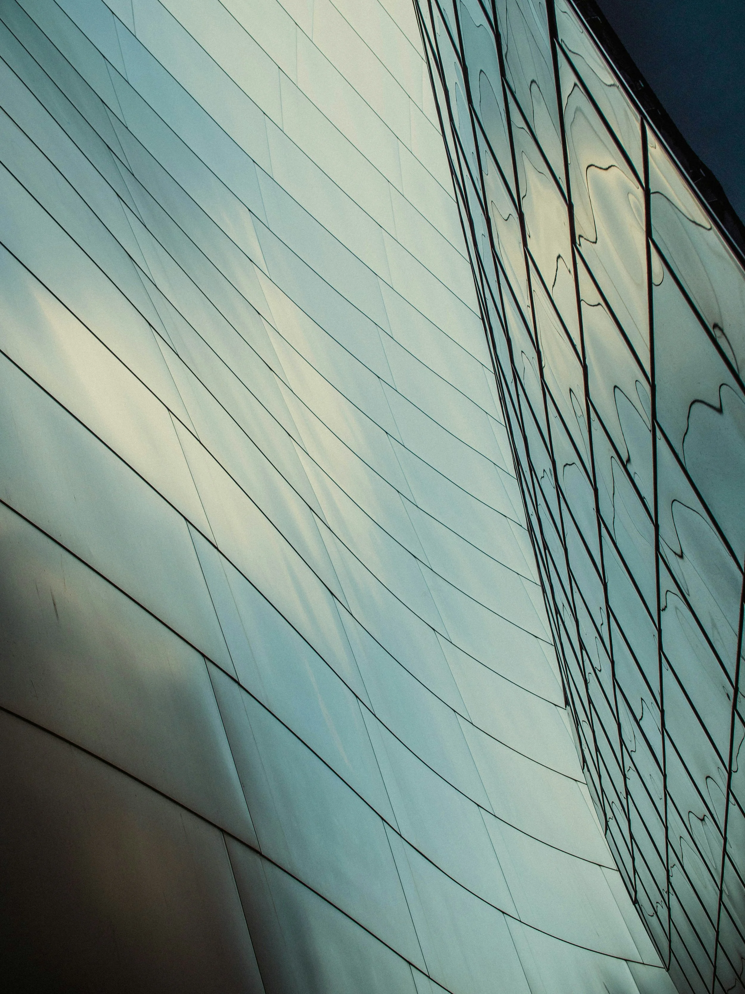 Close-up of modern building facade with reflective glass panels and geometric paneling.