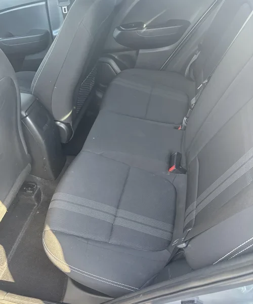 Rear passenger compartment of a Hyundai Venue, showing the cloth bench seat with textured pinstripe detailing, seatbelt hardware, and available legroom space