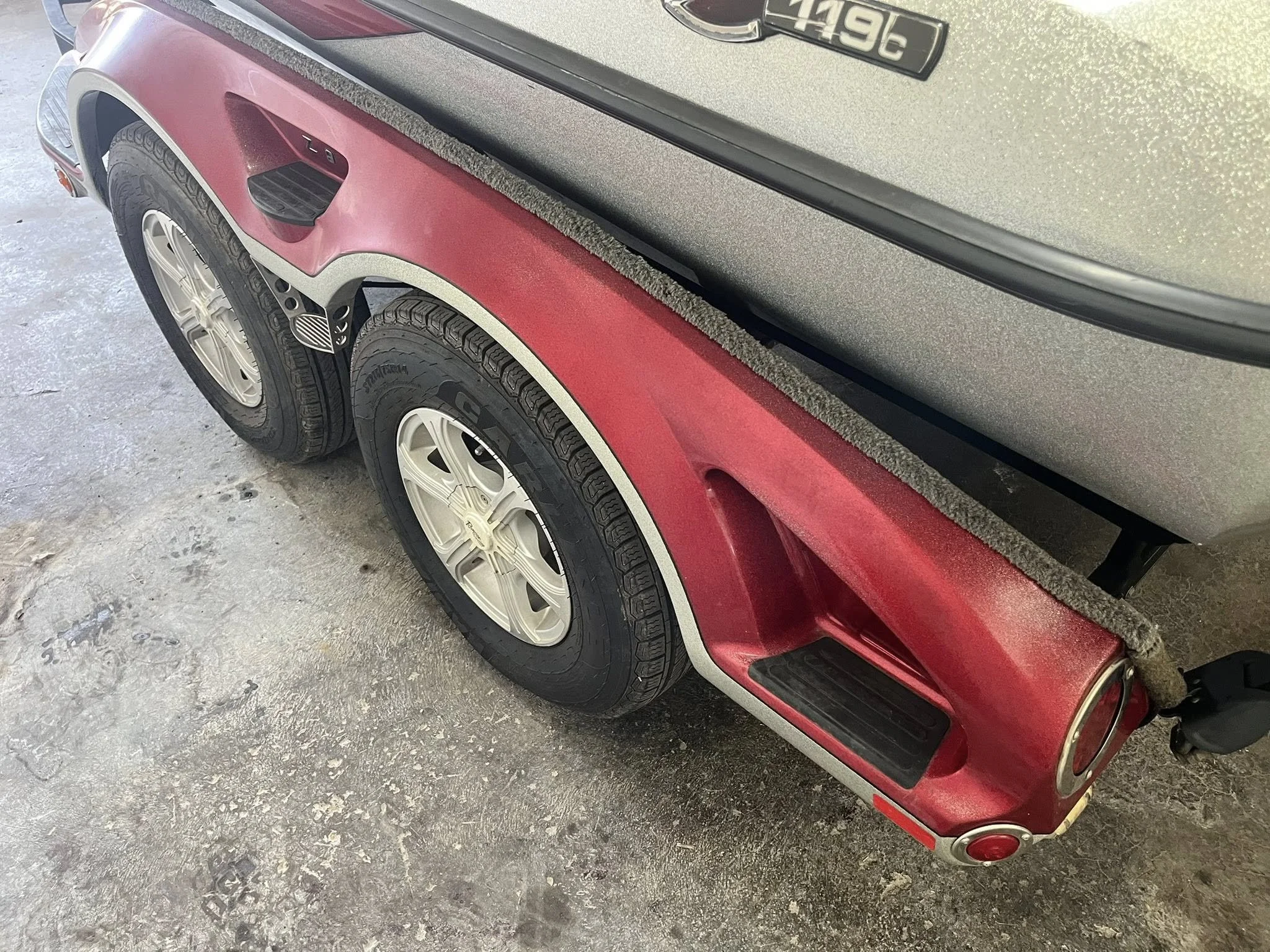 Close-up of the rear wheel and fender of a vintage red and gray golf cart with dual tires.
