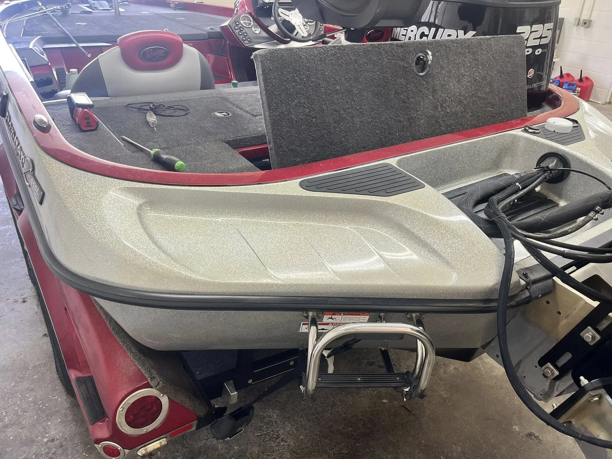 Empty fishing boat with fishing gear and boat motor inside a garage.