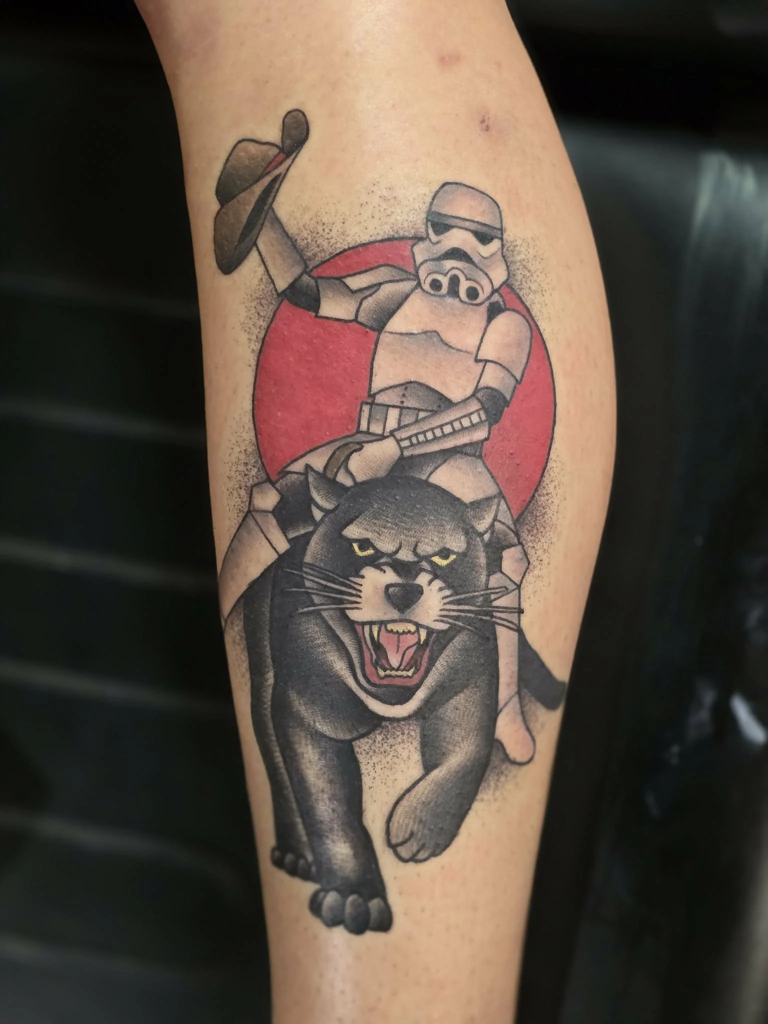 Tattoo of a Star Wars scene with a Stormtrooper on a speeder bike riding a snarling black panther.