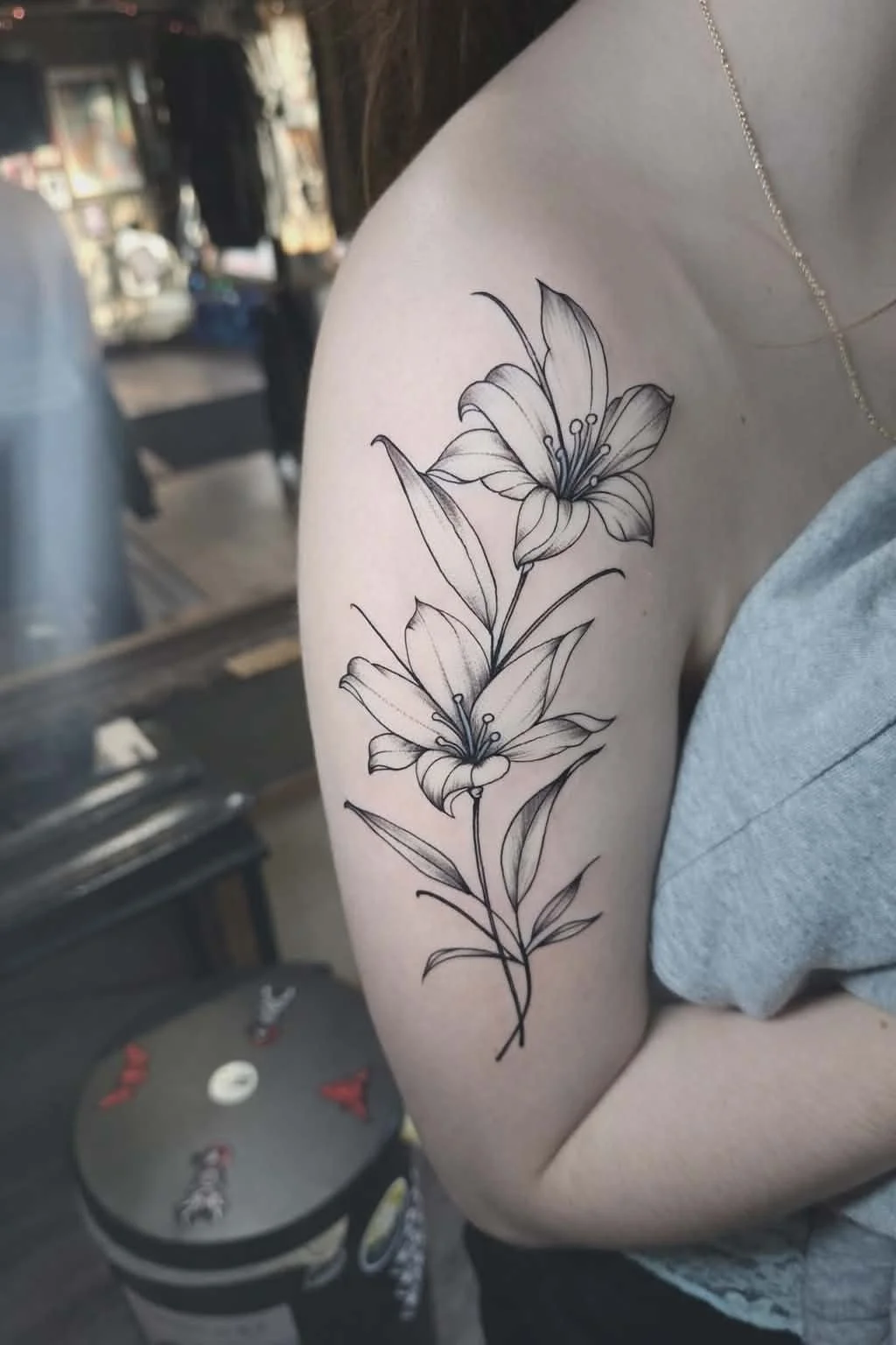 Black and gray floral tattoo of two lilies on a person's upper arm.