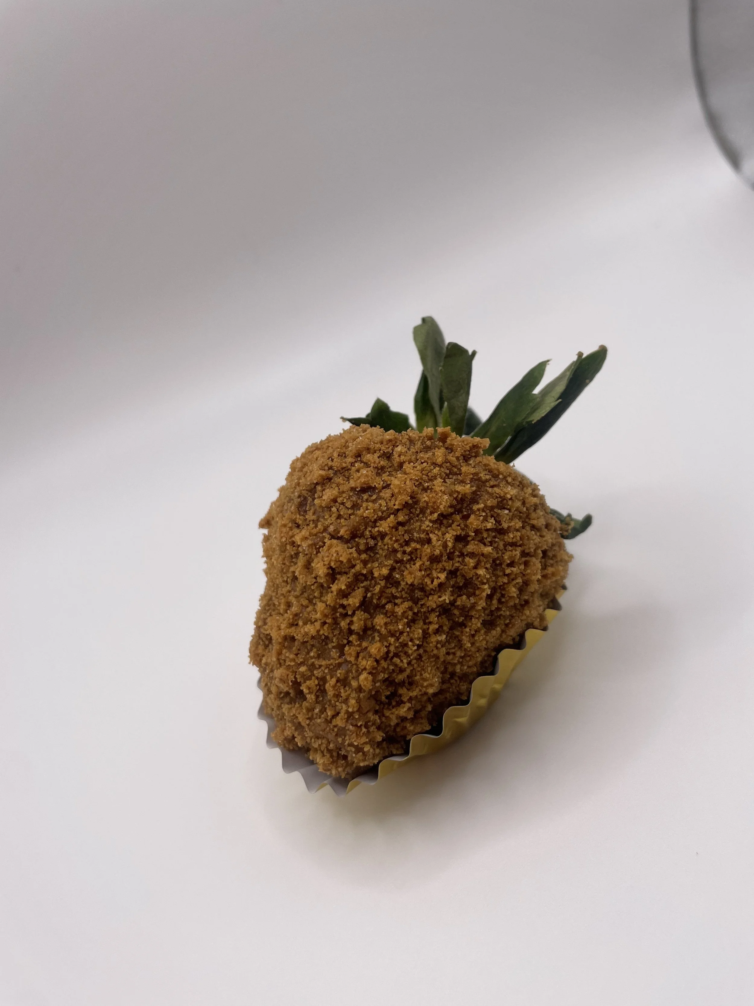 Fried food item with a green garnish on top, placed on a white surface.