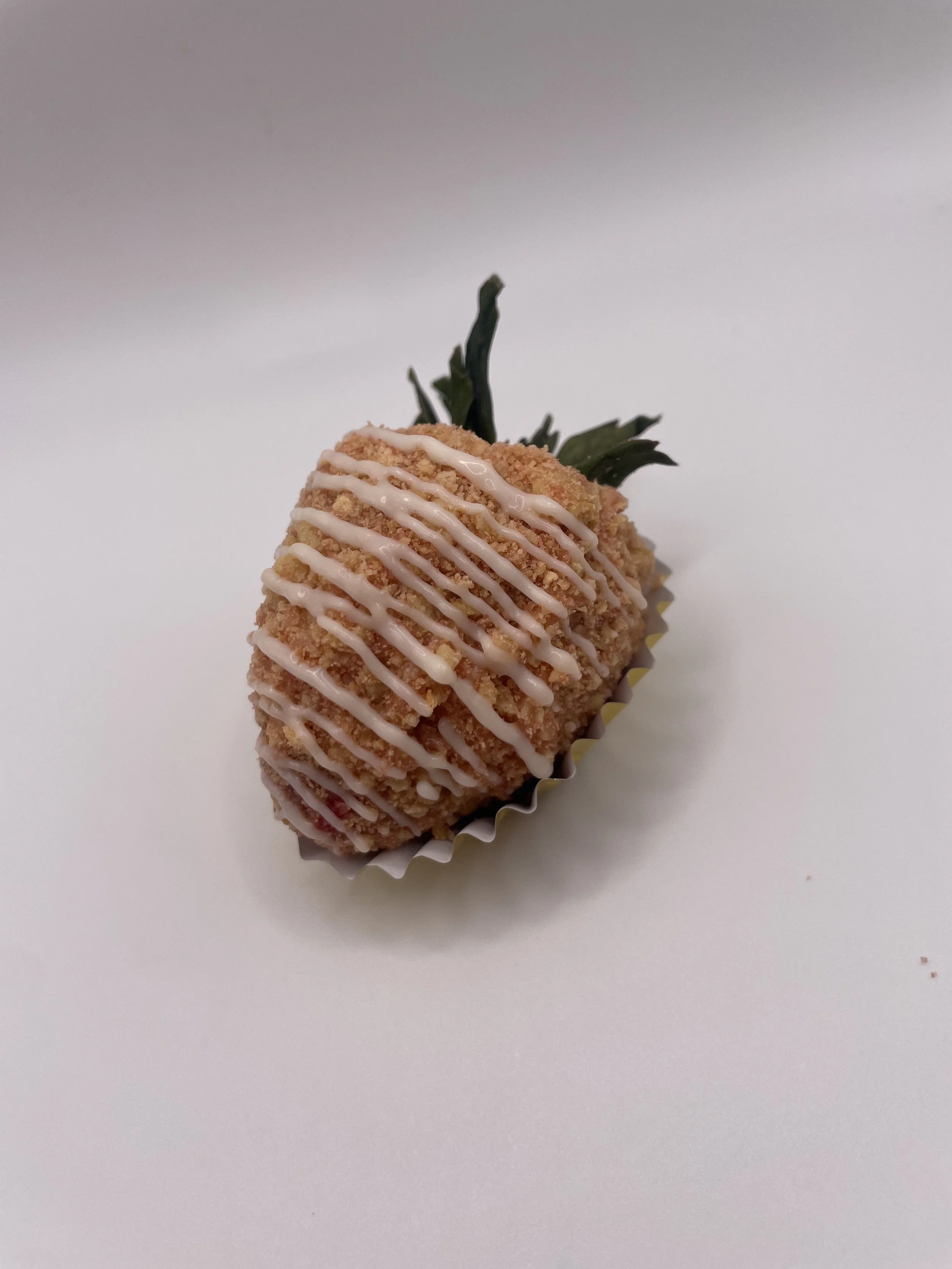 Strawberry dipped in white chocolate, decorated with pink drizzle, placed in a cupcake liner with green leaf at top