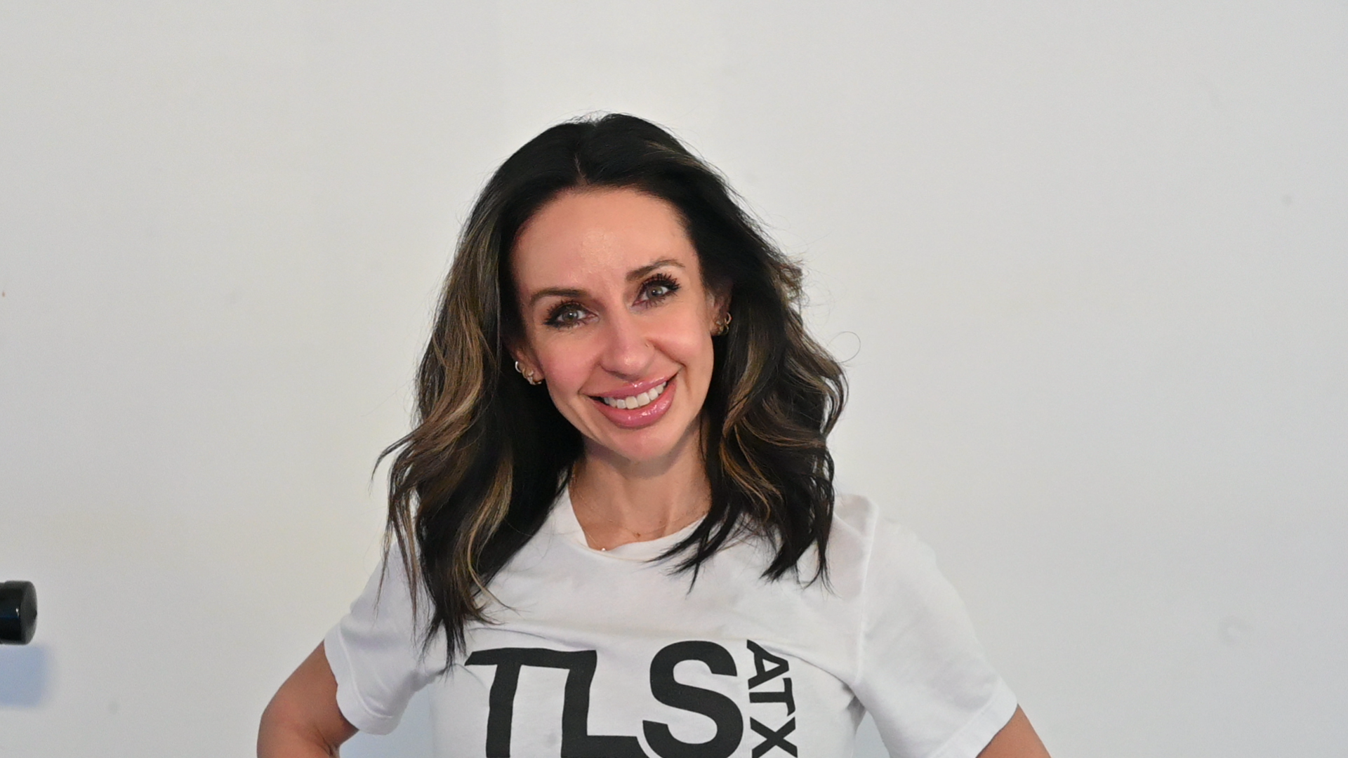 Smiling woman in a white t-shirt against a plain background