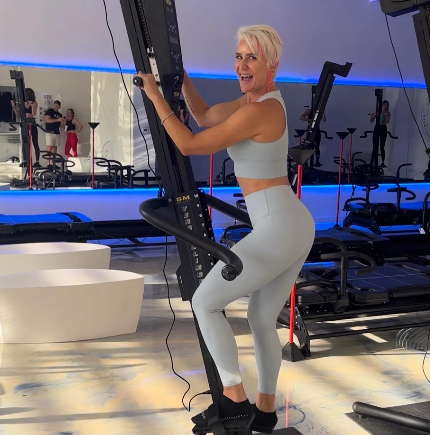 Person exercising on a machine in a gym wearing light blue workout outfit.