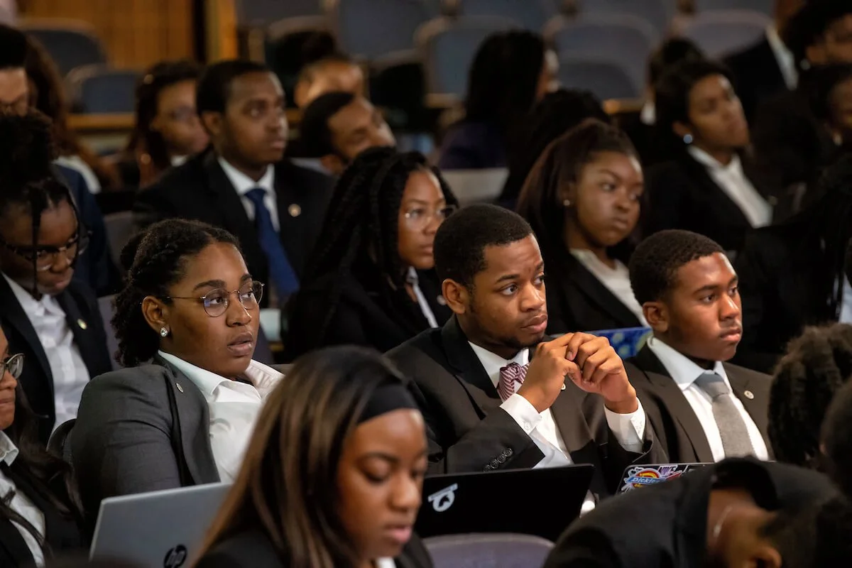 Young professionals at Howard University attentively listening at a conference or seminar, seated in rows, many wearing business attire.