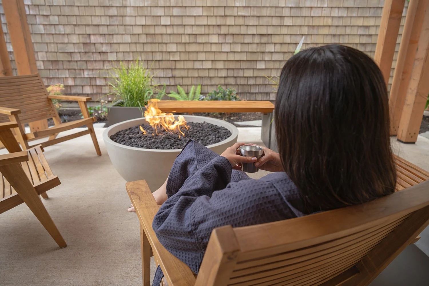 woman in robe resting by fire pit outdoor lounge at Loma Sauna House sauna spa