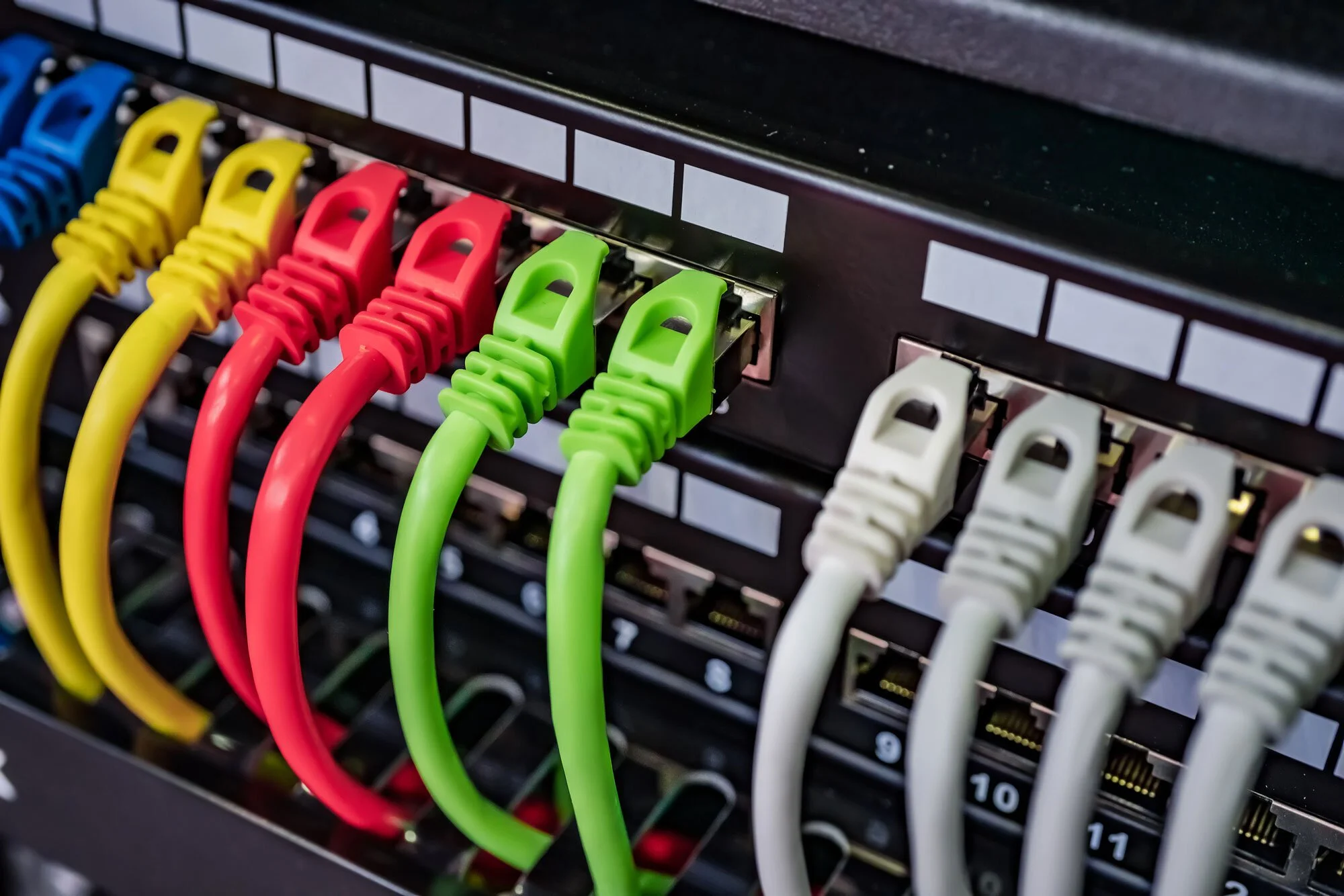 Close-up of network cables in yellow, red, green, and white color plugged into a server or network switch.