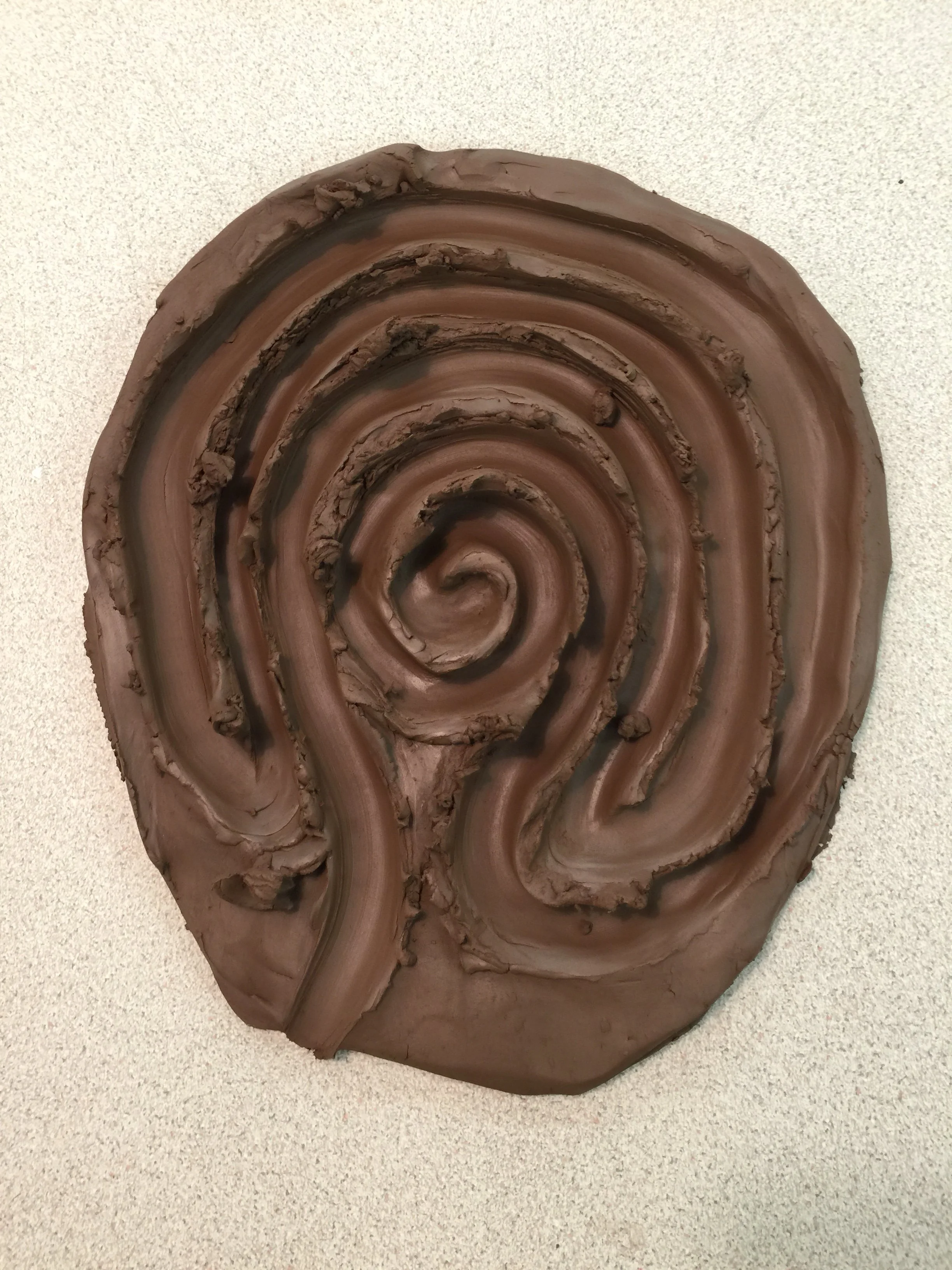 Close-up of a clay sculpture by Camilla Emson of a labyrinth. A symbol for a journey inward, transformation, a spiritual path, returning to the world and self trust.