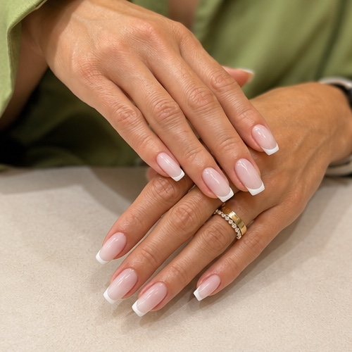Classic French manicure with soft pink base and white tips on square-shaped nail extensions
