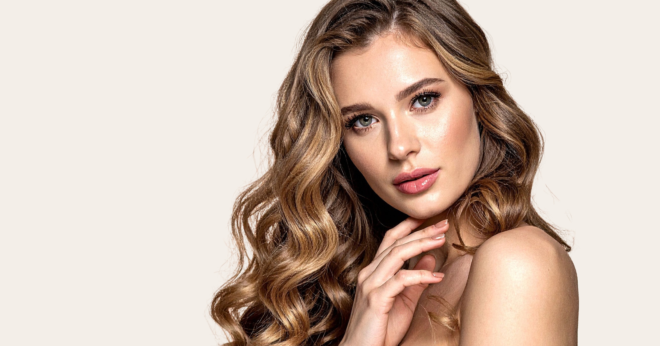 A woman with long, wavy light brown hair and blue eyes looking into the camera with a gentle expression.