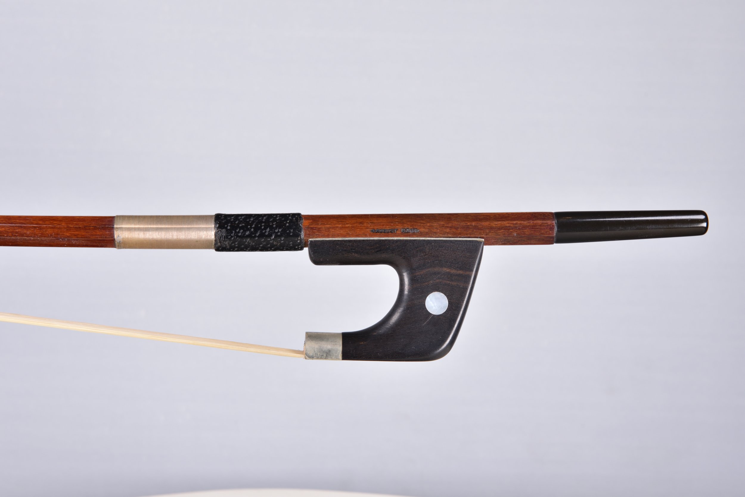 Close-up of a violin with a black chin rest, wooden body, and long bow against a plain white background.