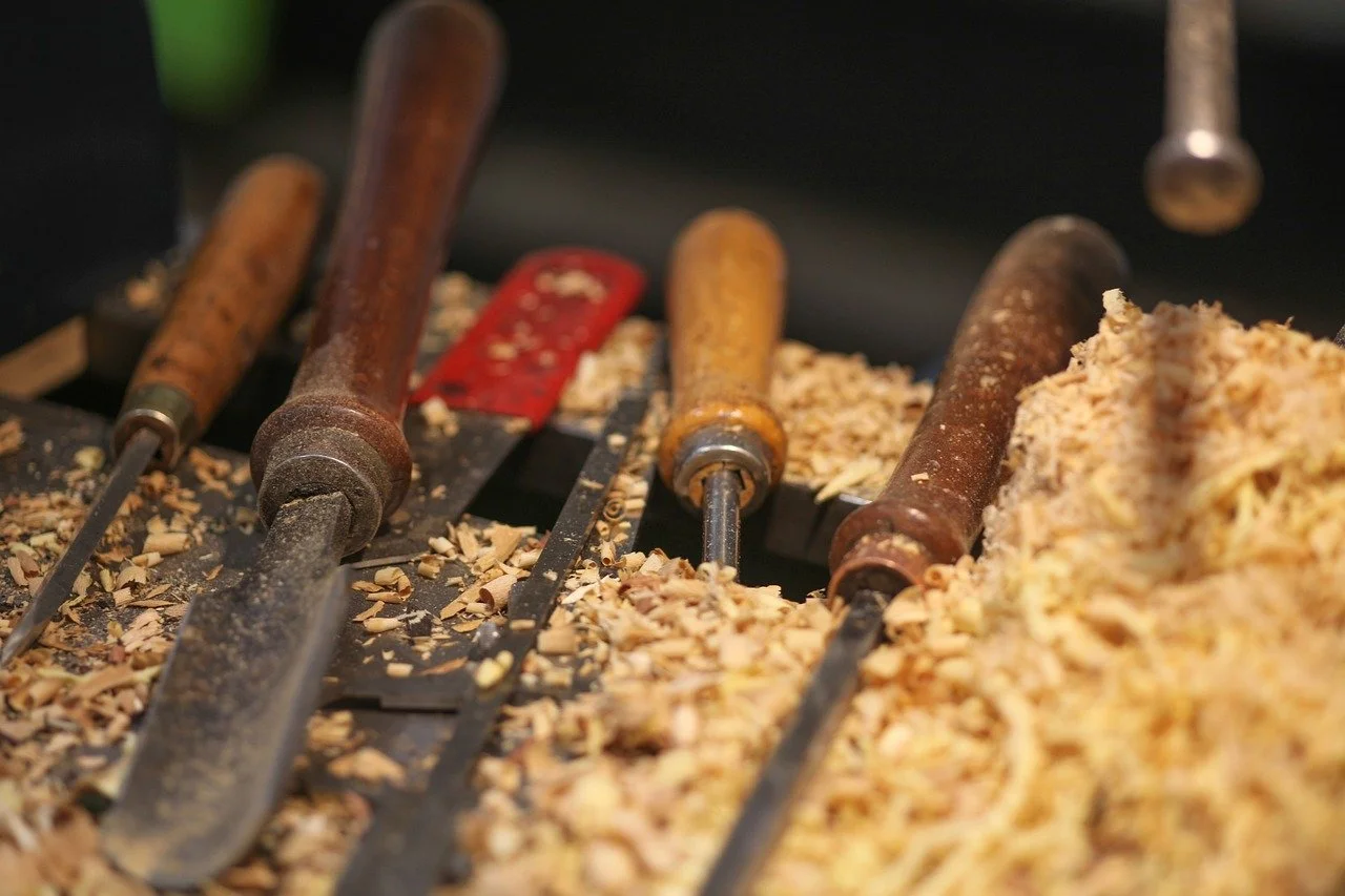 Wood chisels lying on a workbench with wood shavings covering the surface.
