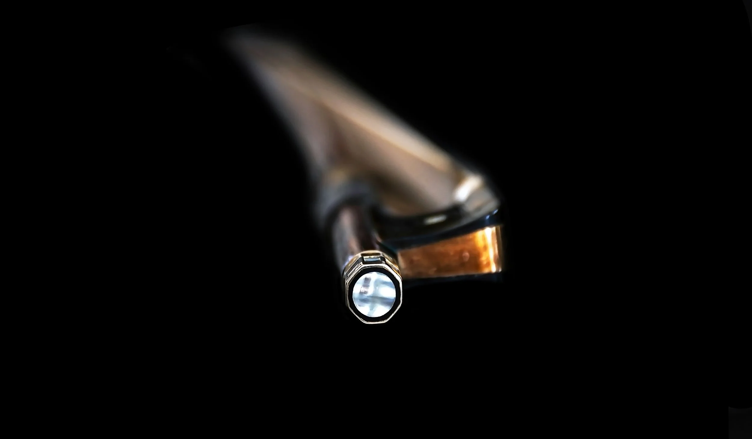 Close-up of a metallic fountain pen tip against a black background.