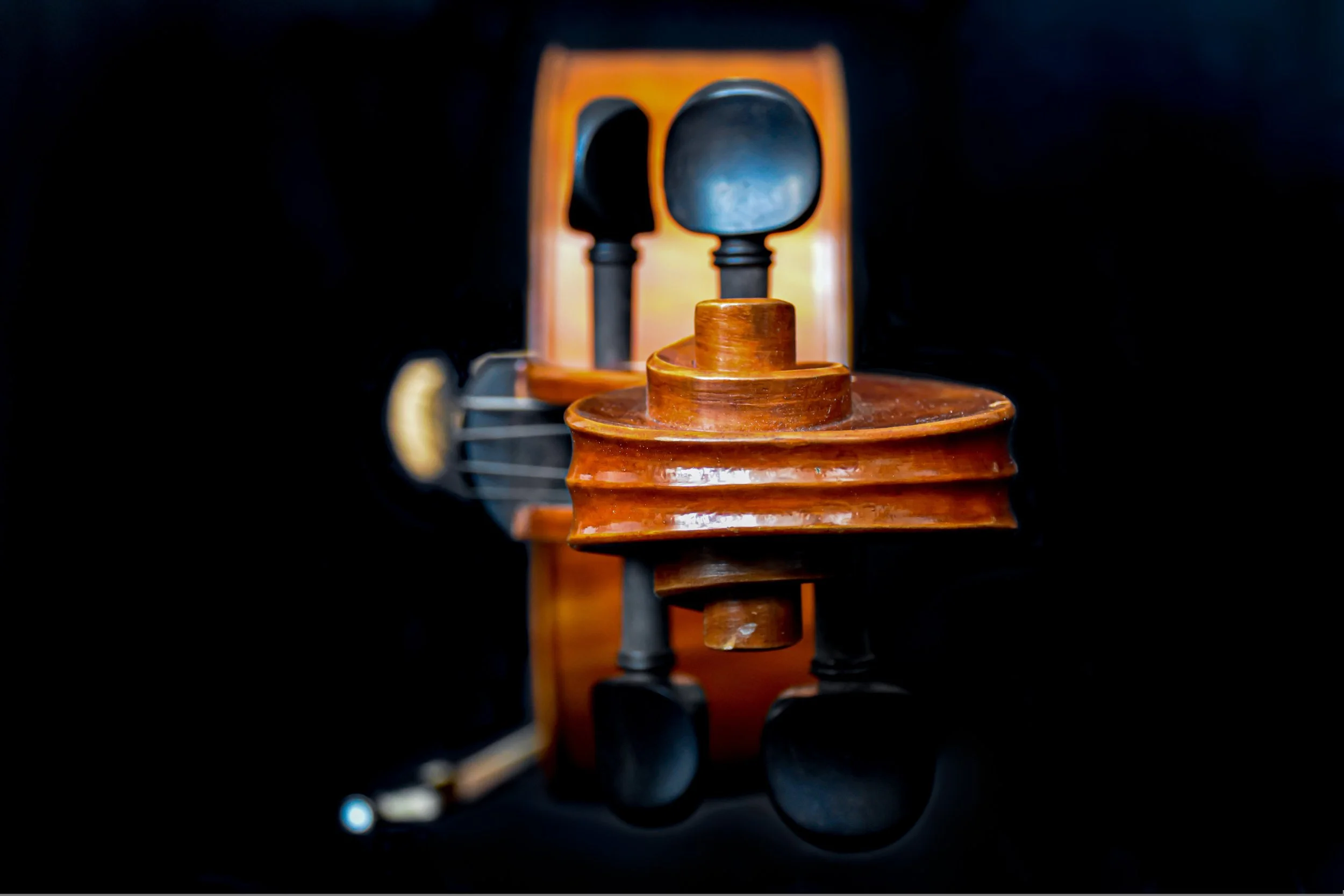 Close-up of a wooden figurine or sculpture with black head and limbs, set against a dark background with a reflecting surface.