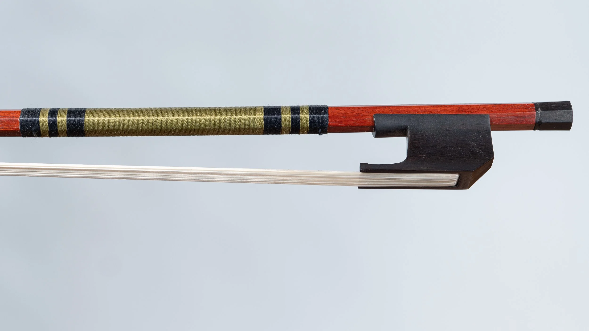 A close-up of a violin with a wooden neck, black pegs, a black fingerboard, and a bow with white horsehair against a light gray background.