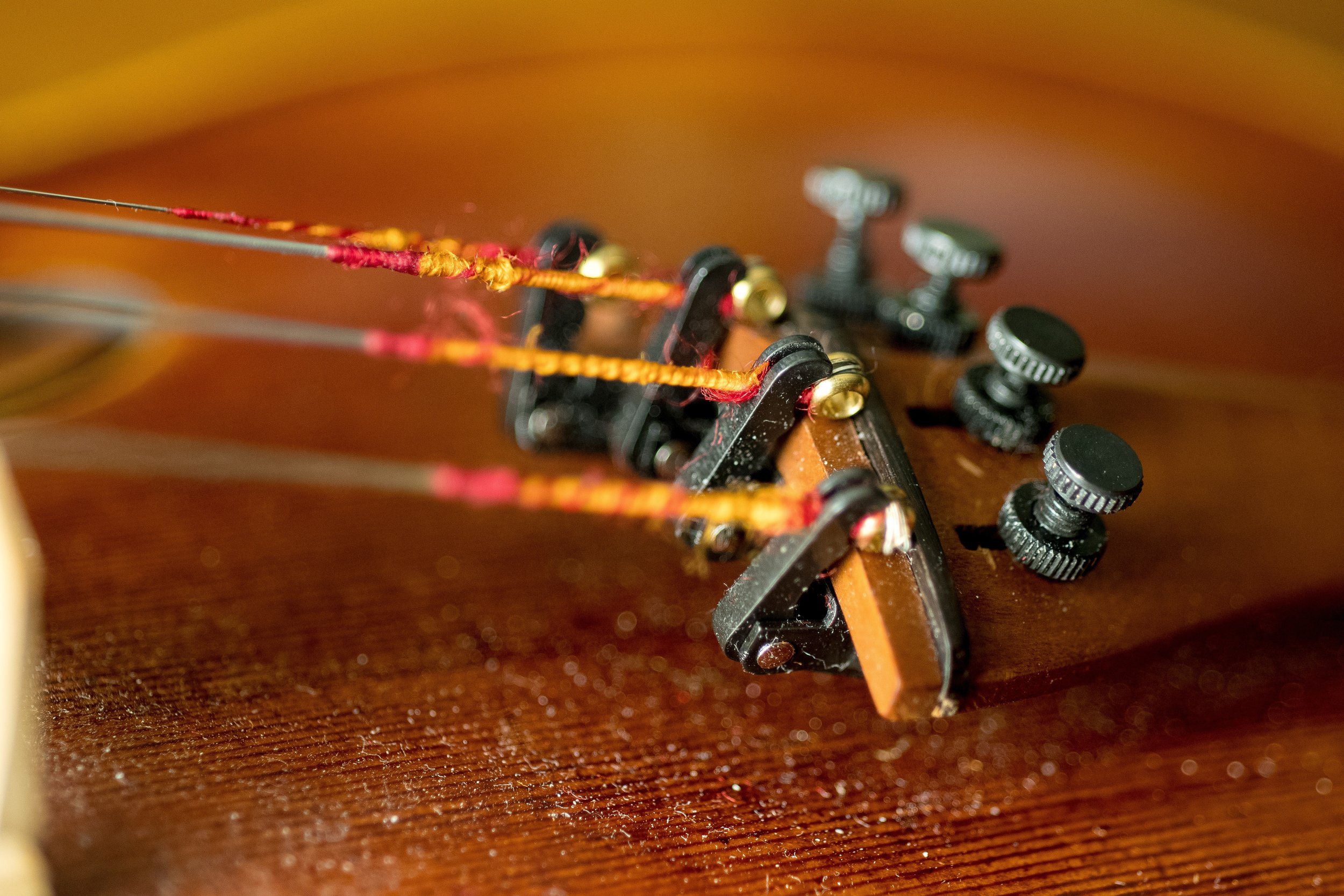 Close-up of the tuning pegs and strings on a wooden acoustic guitar.