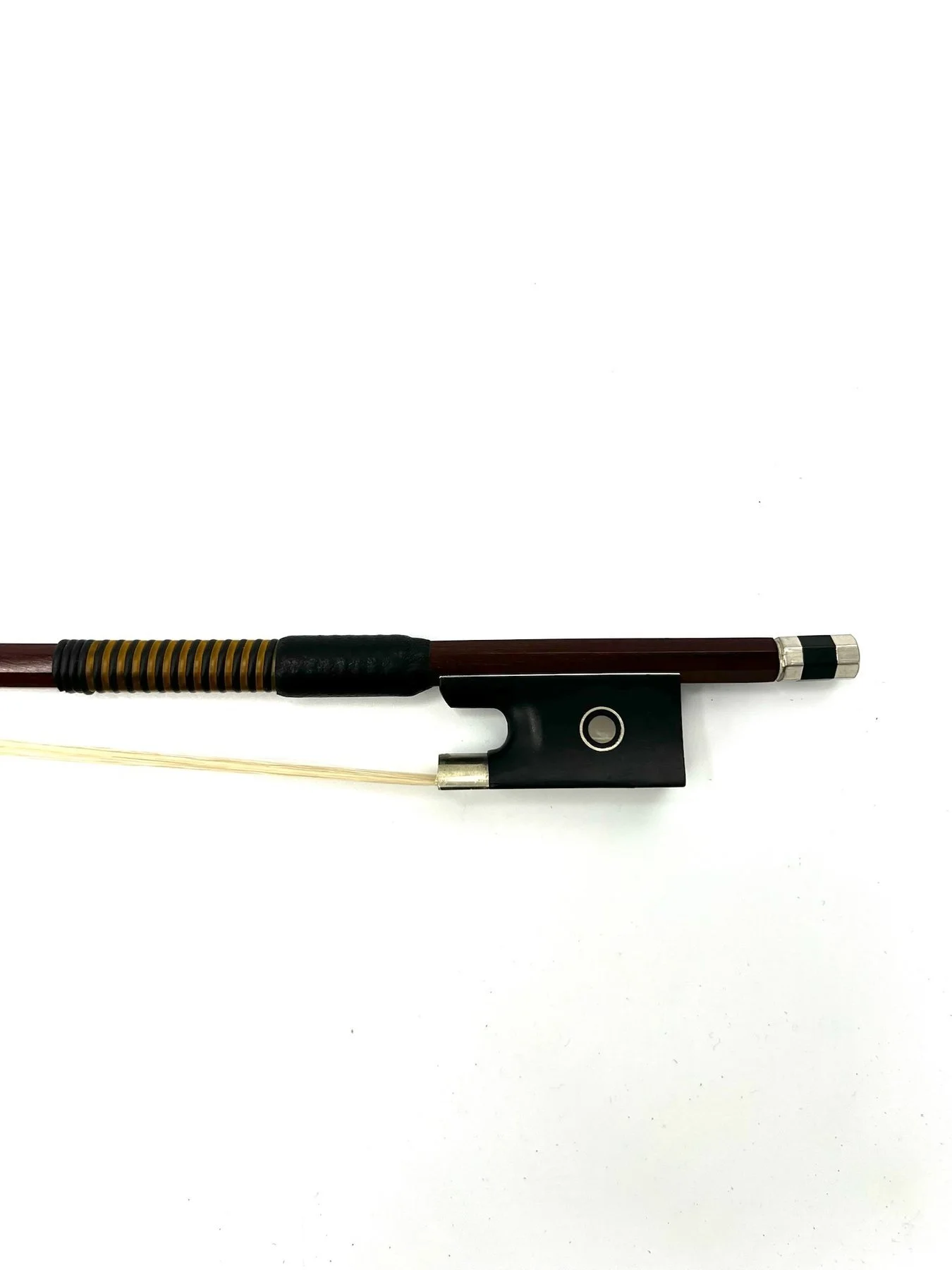 Close-up of a violin bow lying on a plain white surface.