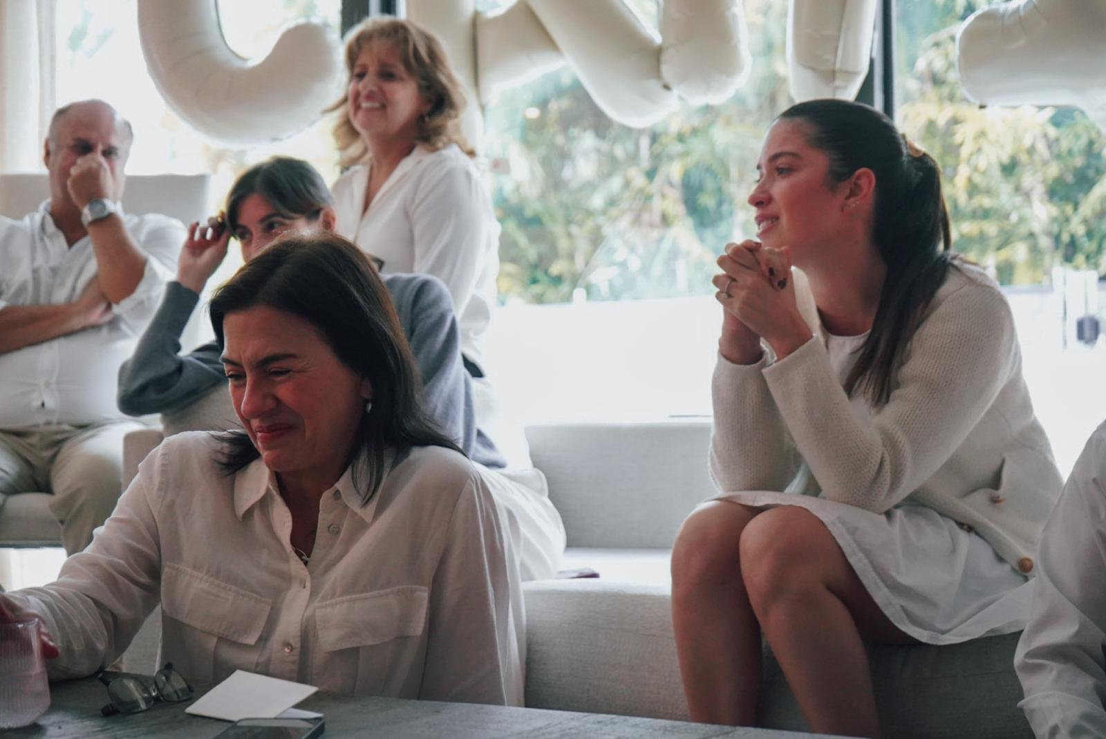 Group of people indoors, with some crying and others smiling, during an emotional moment.
